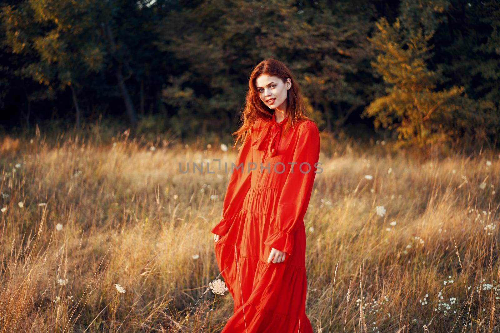 woman in a red dress in a field in nature summer landscape freedom. High quality photo