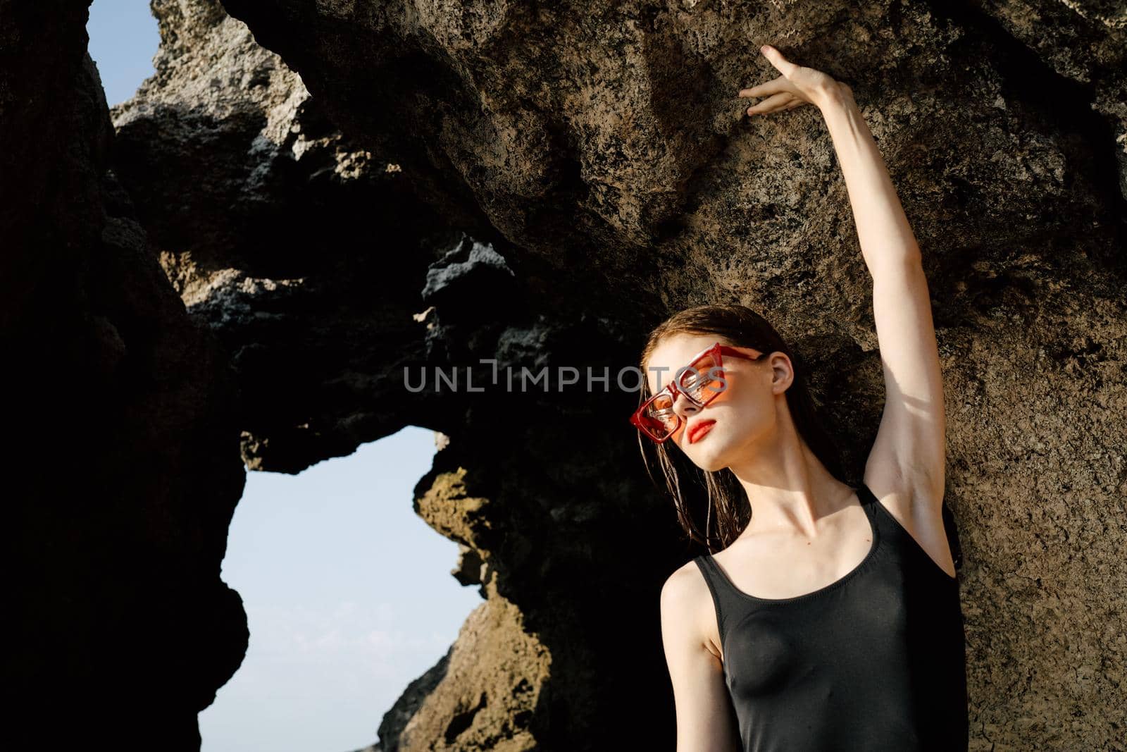 woman in black swimsuit sunglasses summer rocks exotic. High quality photo