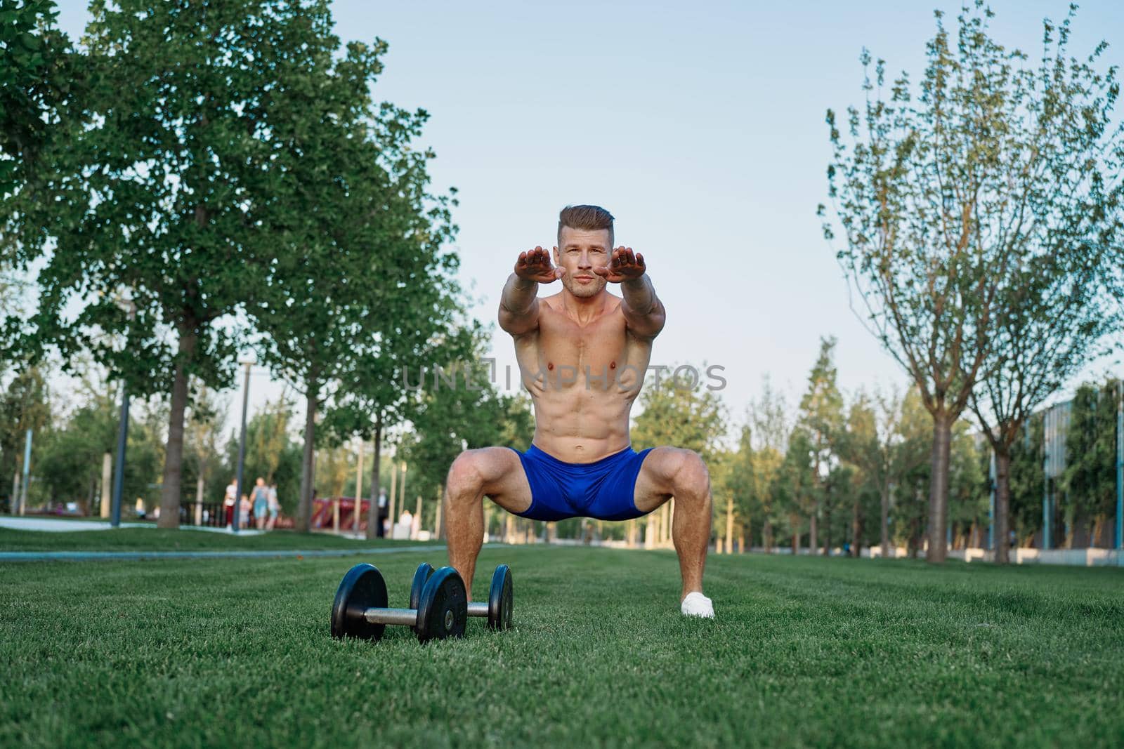 Muscled man in the park training with dumbbells. High quality photo