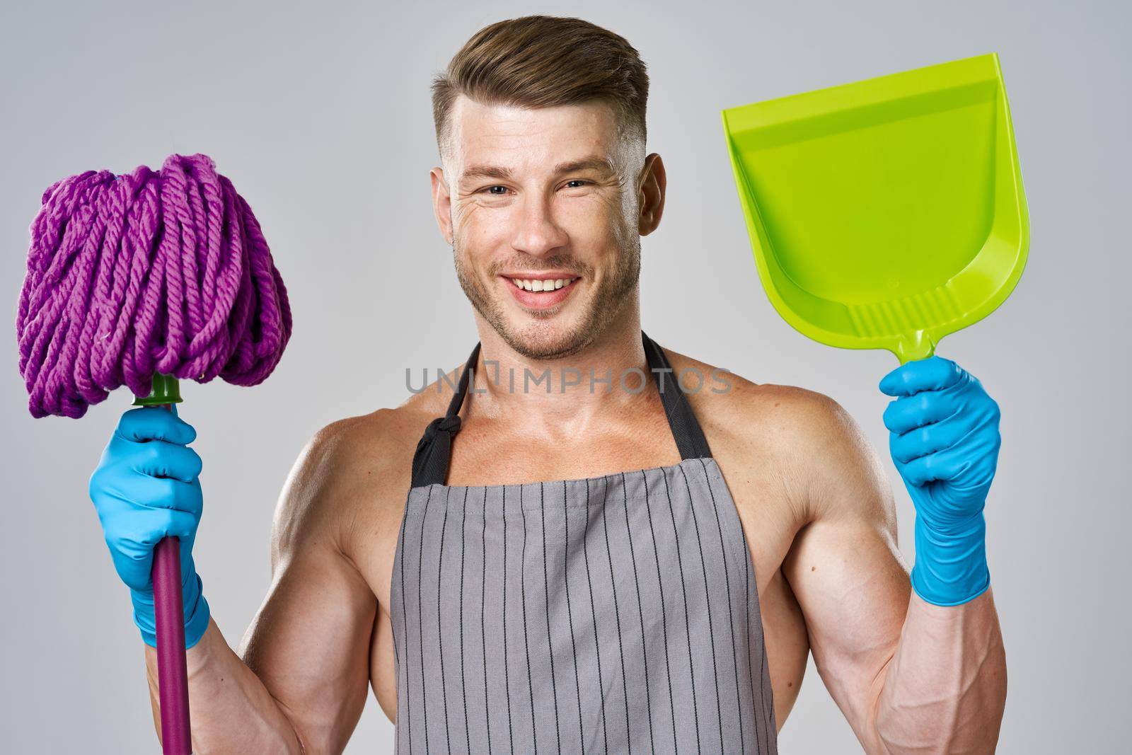 Muscled man in apron with mop posing cleaning. High quality photo