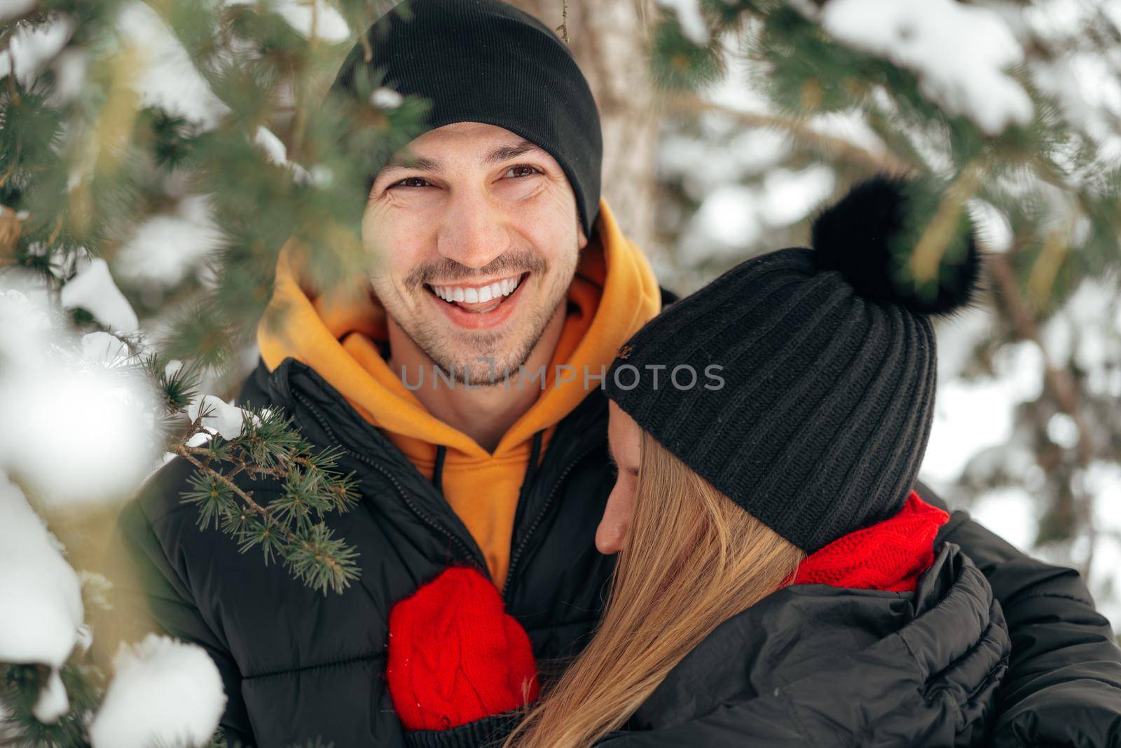 Close up of young couple in warm clothes standing together in a winter park by Fabrikasimf