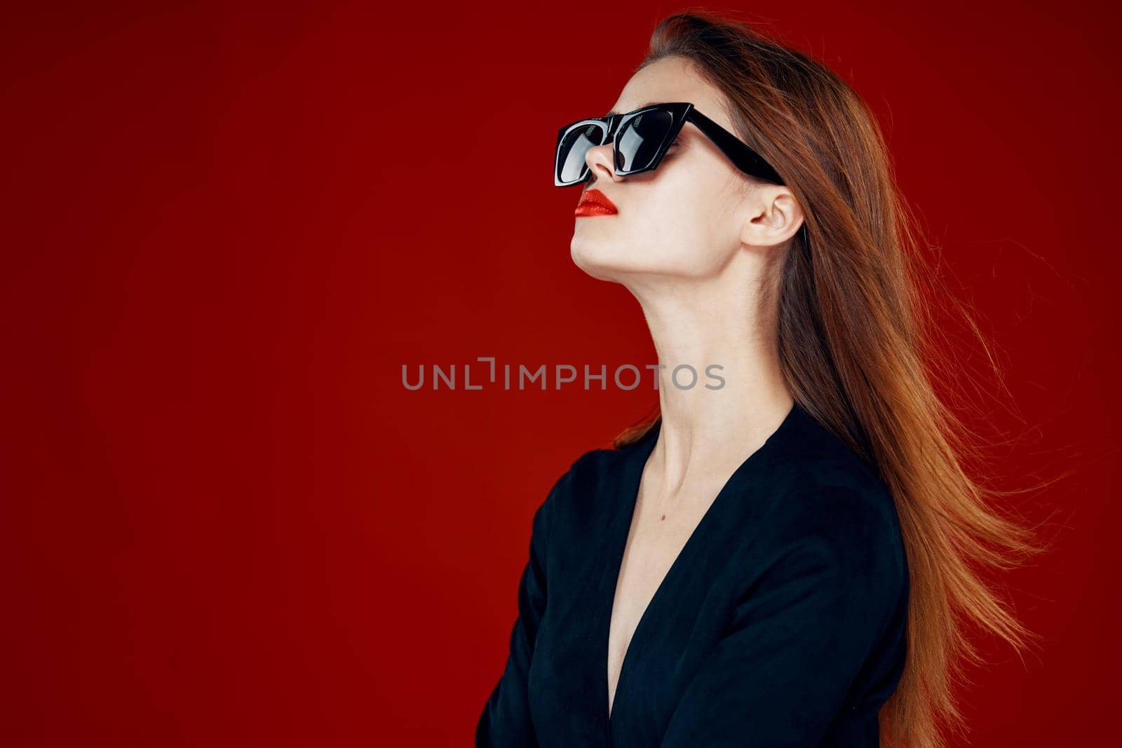 cheerful fashionable woman wearing sunglasses red lips posing red background. High quality photo