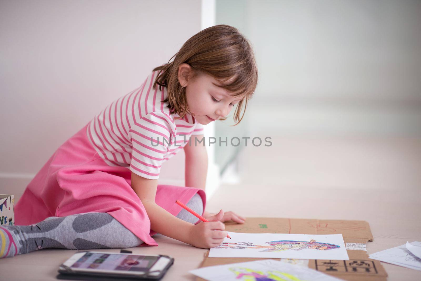 child playign at home while drawing colorful art and looking digital tablet