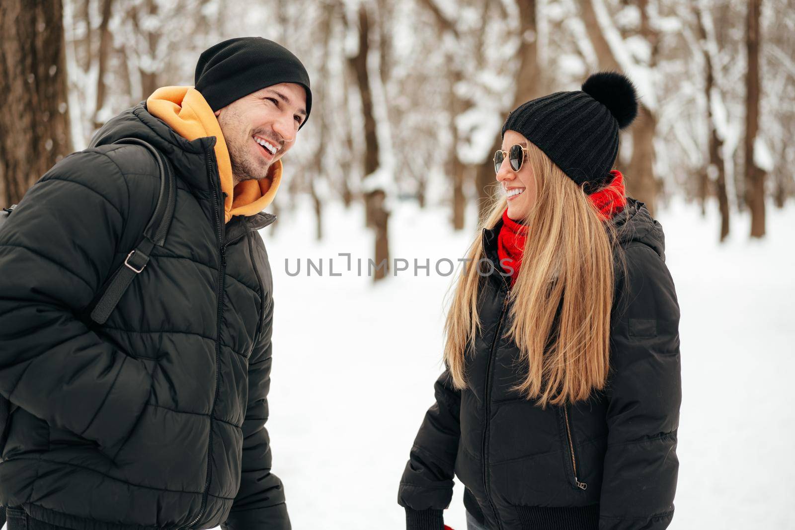 Happy couple hugging and smiling outdoors in snowy park by Fabrikasimf