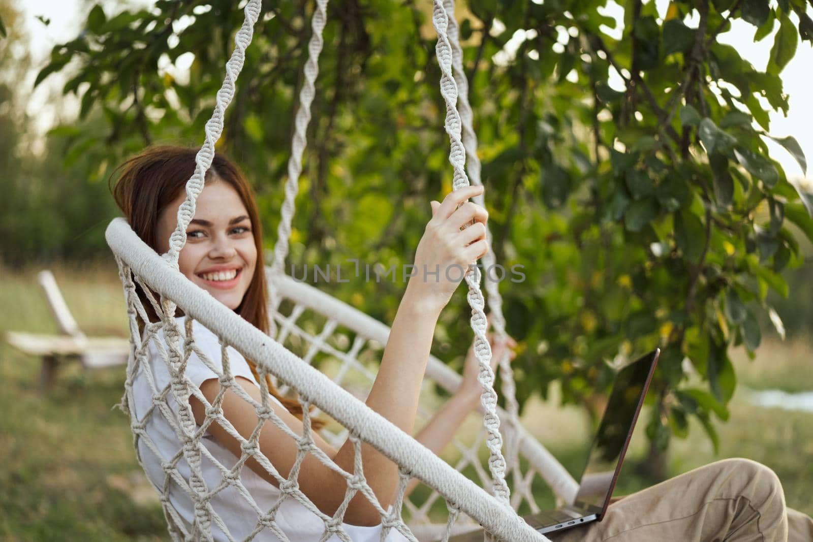 woman with laptop outdoors resting in hammock internet. High quality photo