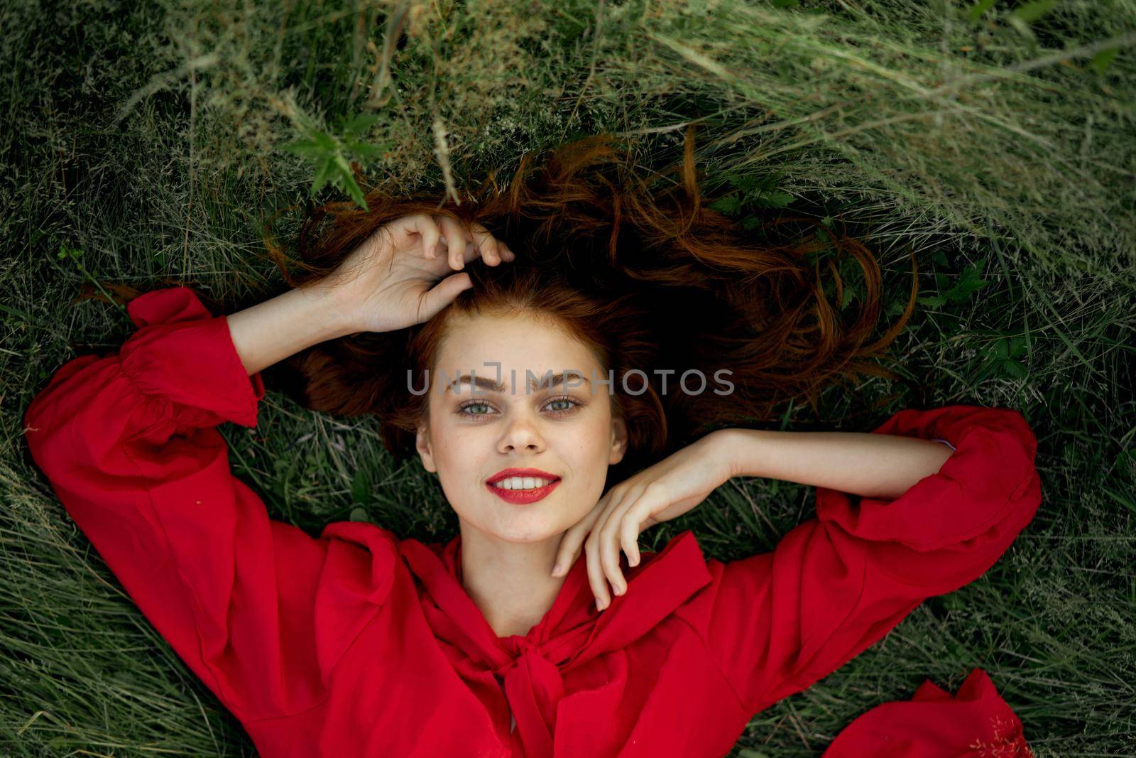 woman in red dress lies on the grass top view freedom. High quality photo