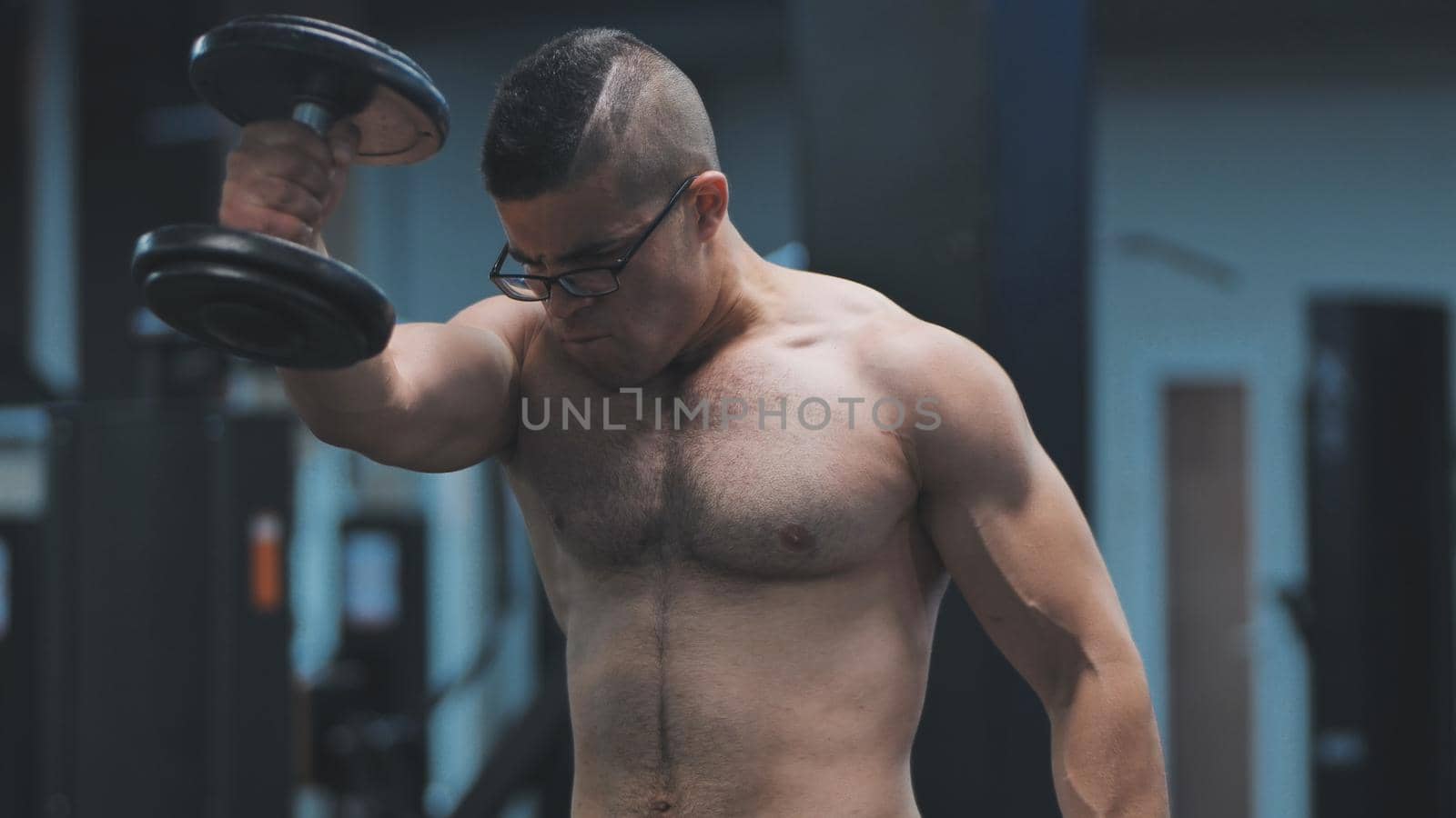Muscular arab man training with dumbbells in the gym