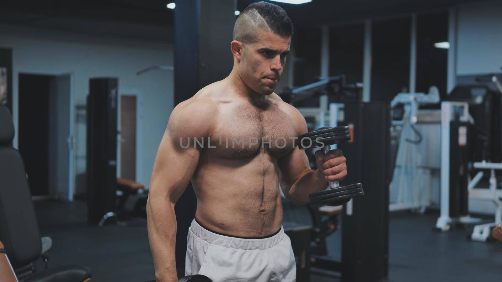Muscular arab man training with dumbbells in the gym
