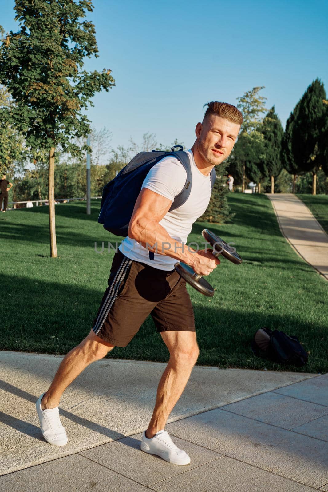 athletic man with dumbbells outdoors at CrossFit park. High quality photo