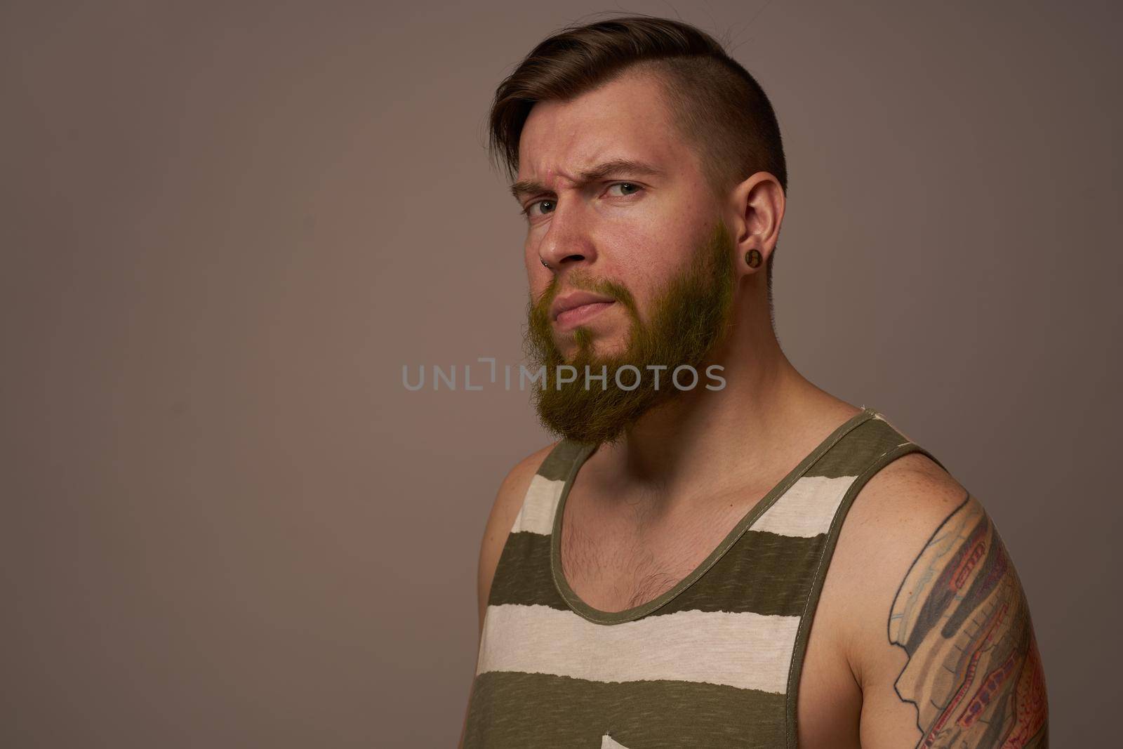 fashionable man with tattoos on his arms stylish hairstyle self-confidence studio. High quality photo