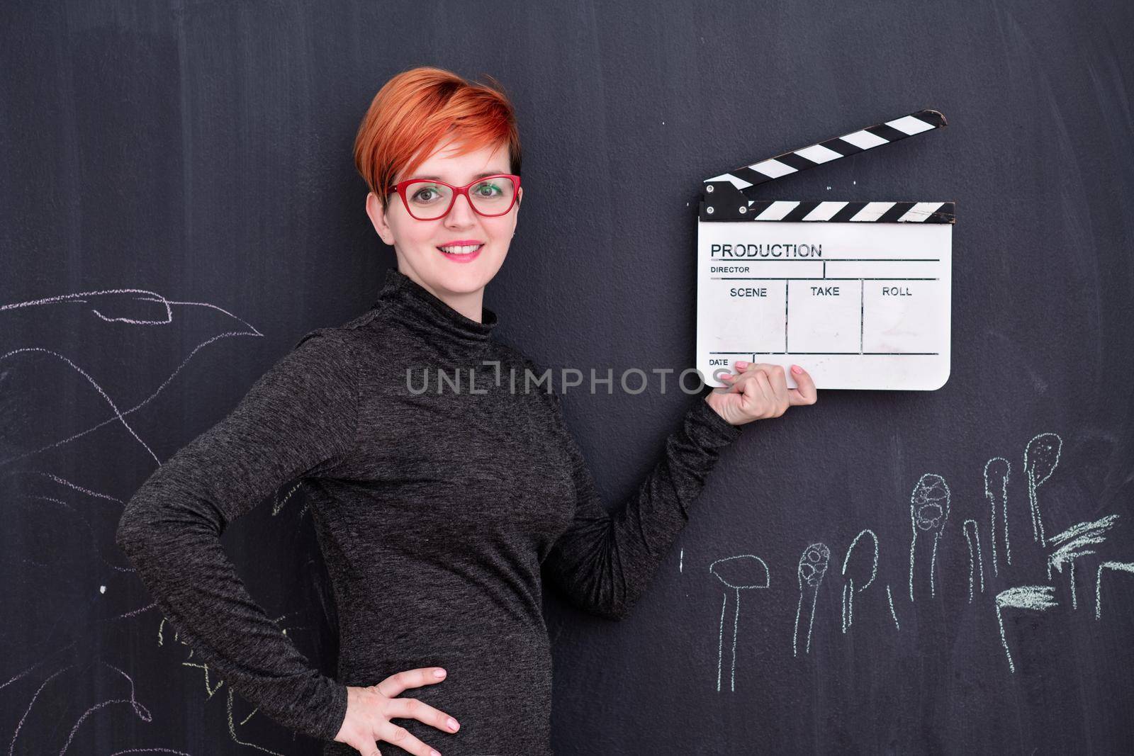 redhead woman holding clapper on black background by dotshock
