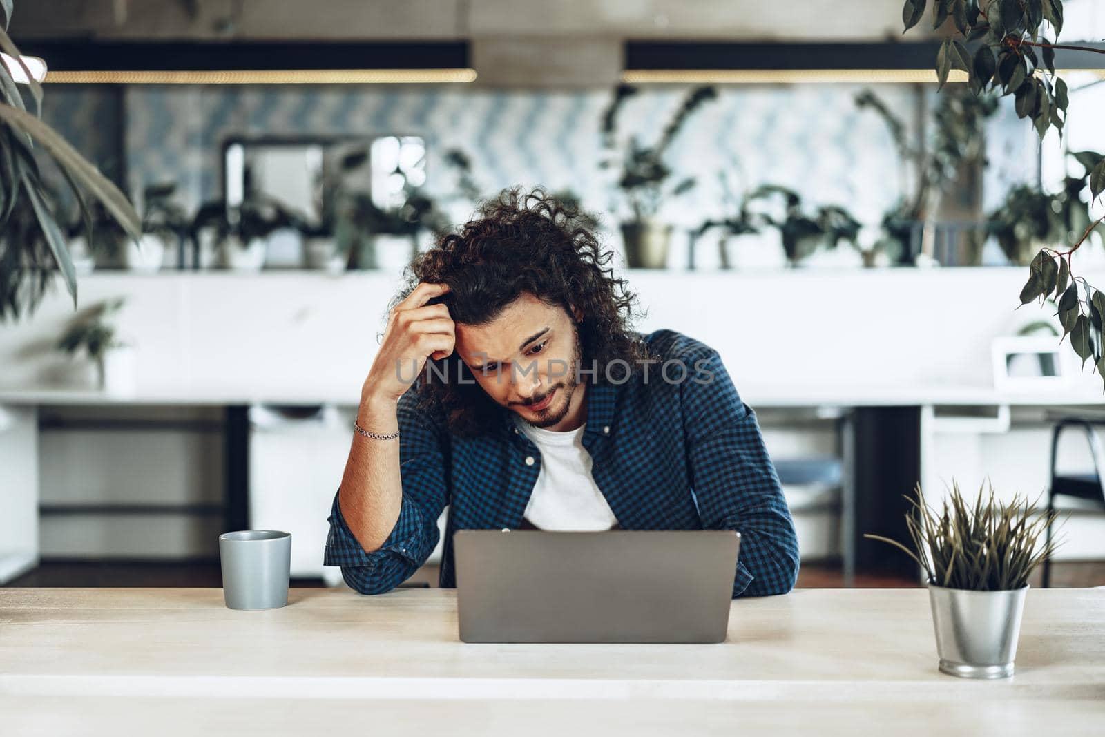Portrait of Young businessman sitting at working table in office and pondering something