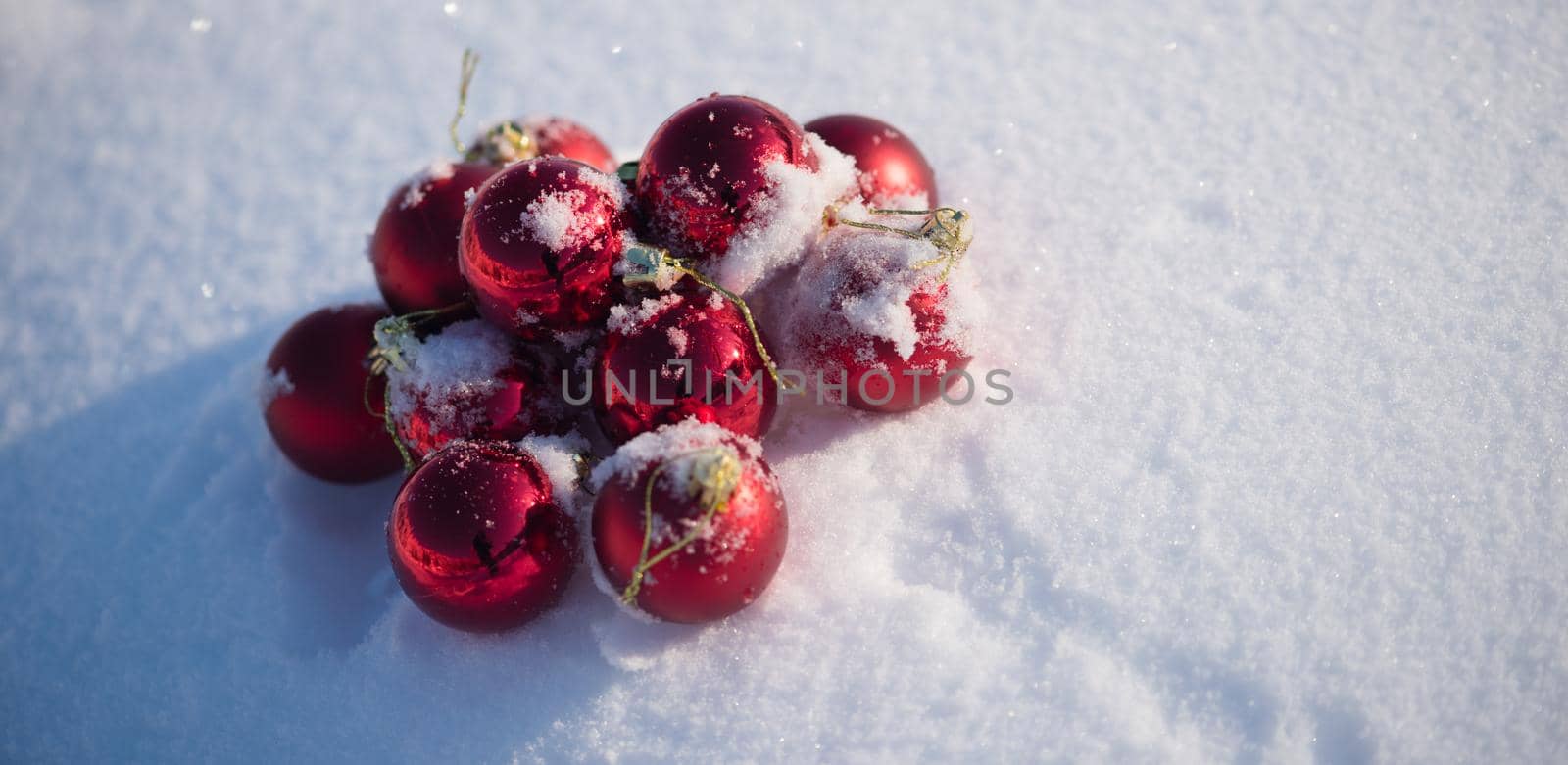 christmas red balls with long shadows  in fresh snow on beautiful sunny winter day