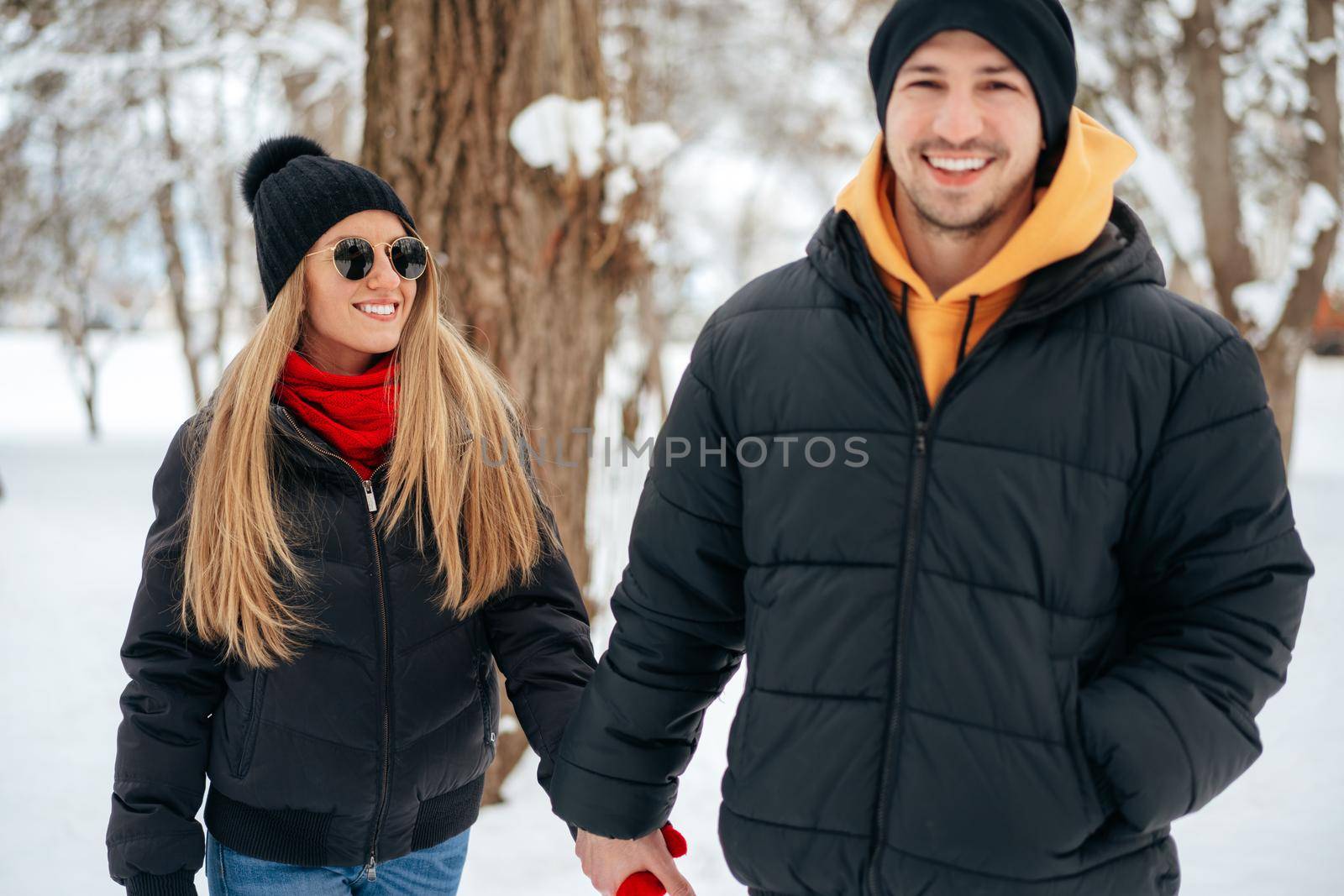 Happy couple hugging and smiling outdoors in snowy park close up