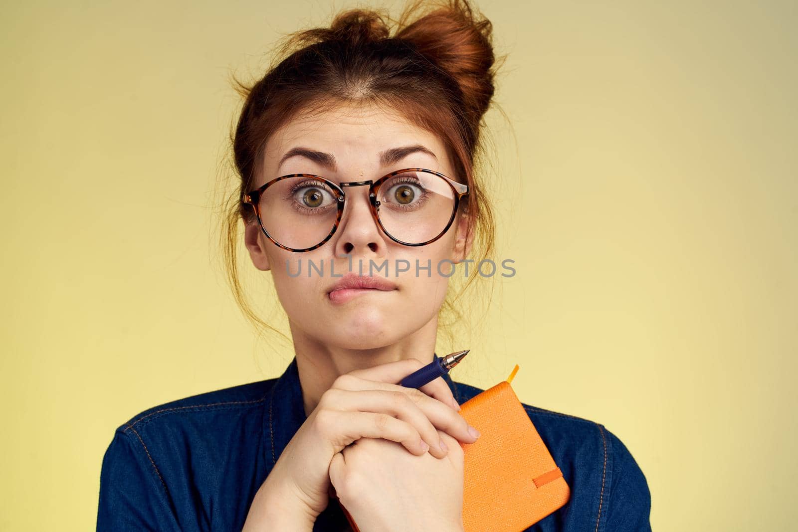 woman student with glasses notepad with pen yellow background. High quality photo