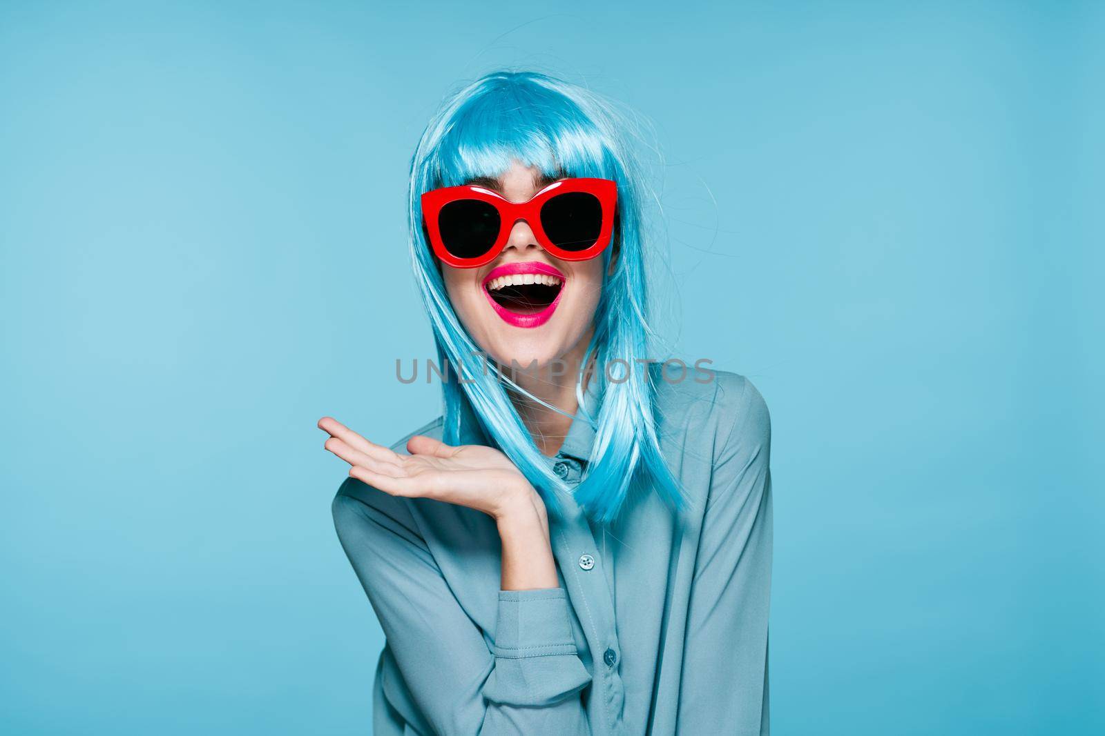 joyful woman purple wig fashion glasses hand gestures blue background. High quality photo