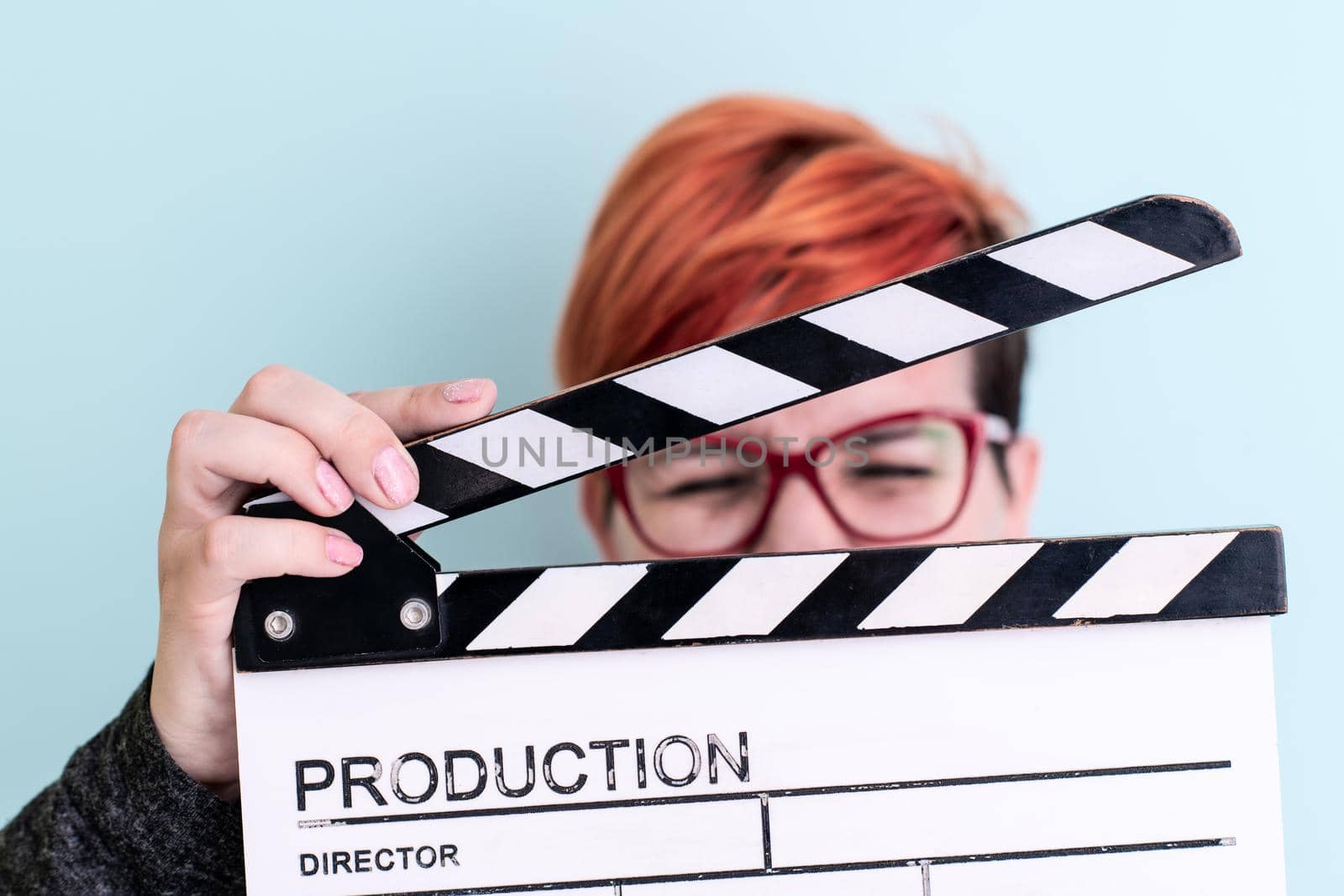 woman holding movie clapper against cyan background by dotshock