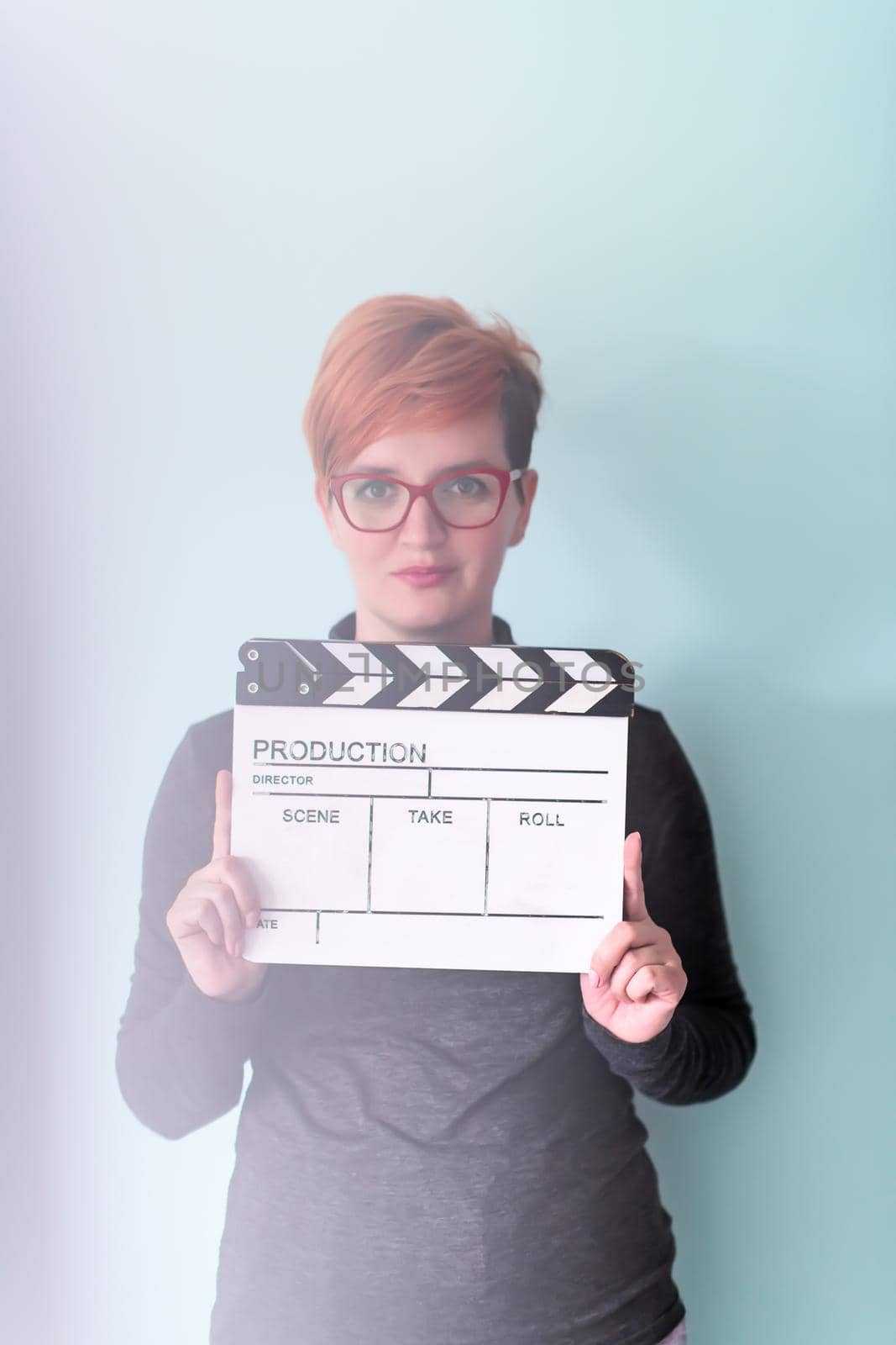 redhead woman holding movie clapper against cyan background cinema concept