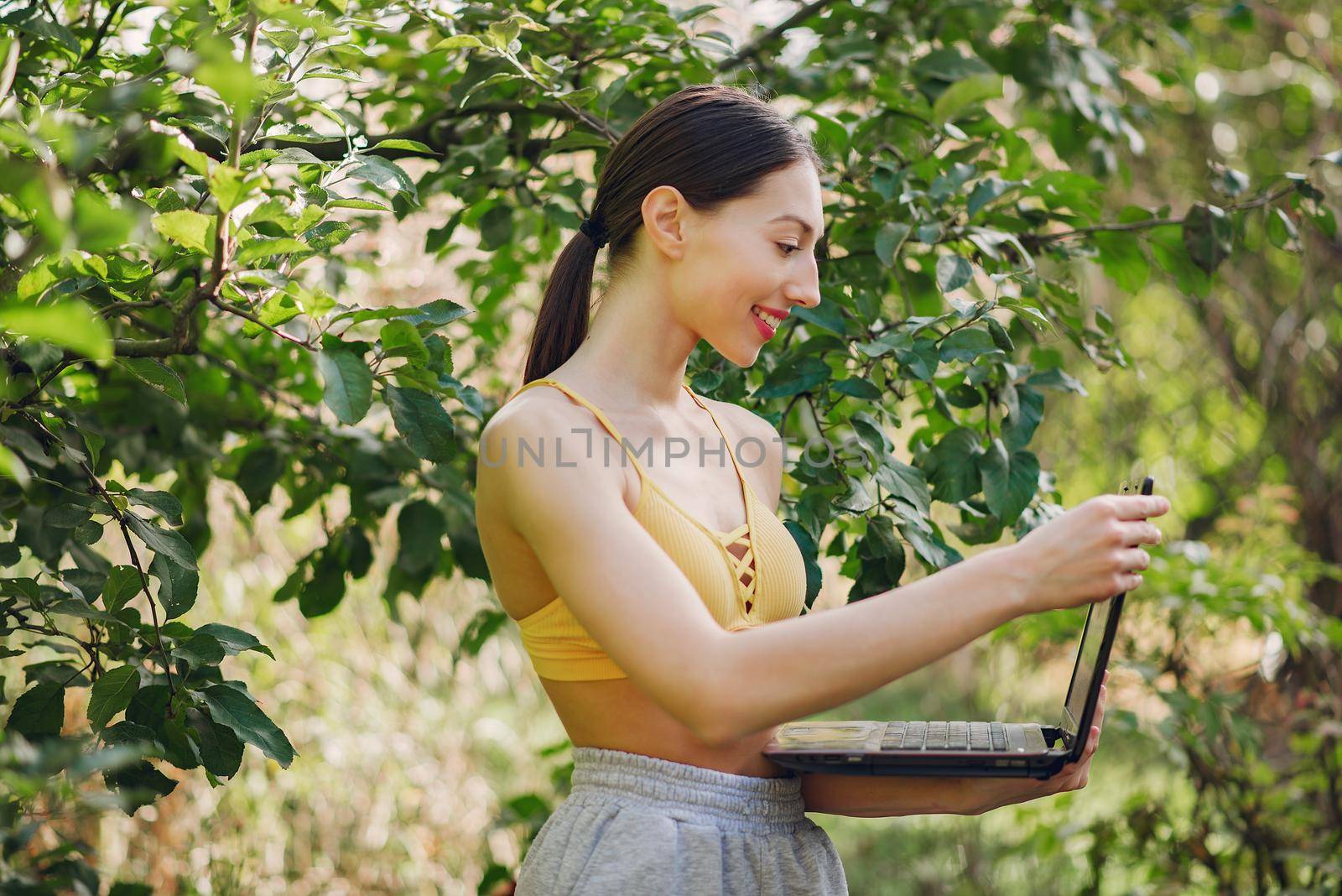 Girl standing in a summer park and holding a laptop in her hands by prostooleh