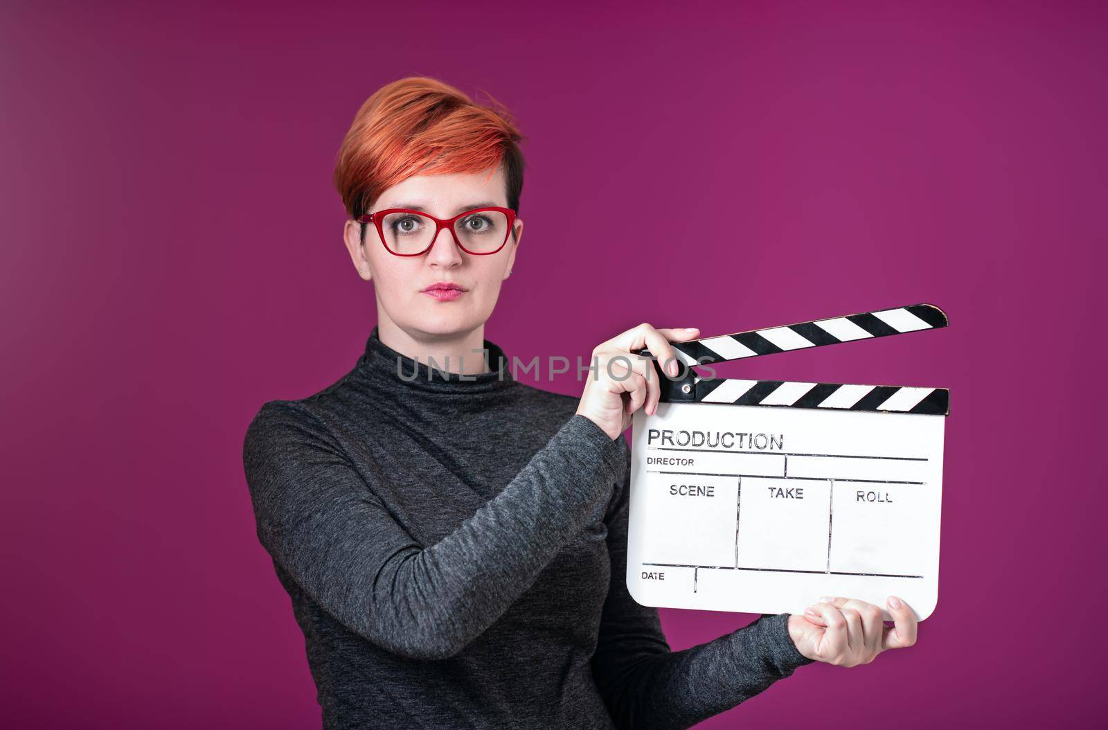 woman holding movie clapper isolated on pink background by dotshock
