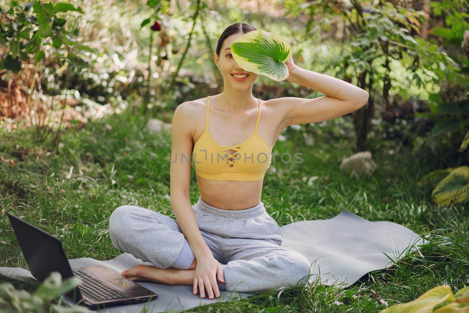 Girl sitting in a summer park and holding a laptop in her hands by prostooleh