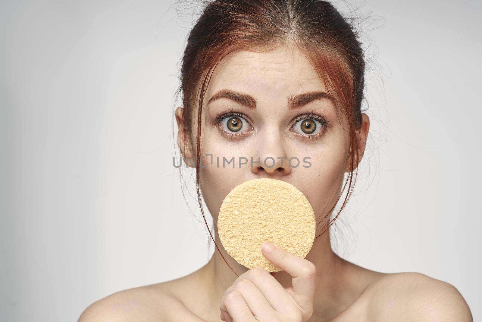 woman with a sponge in her hands bare shoulders skin care closeup by Vichizh
