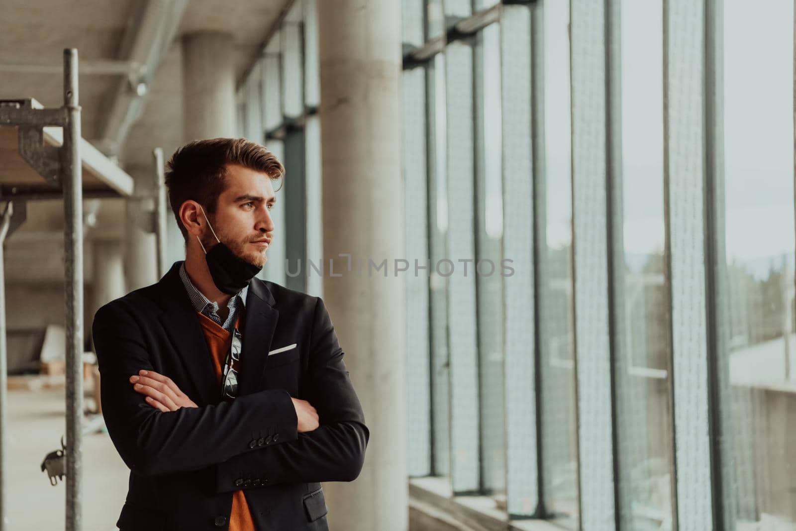 a successful entrepreneur in a suit oversees the construction of the project while wearing a mask against root virus protection