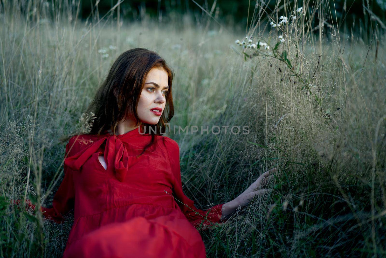 woman in red dress lies on the grass nature freedom rest. High quality photo