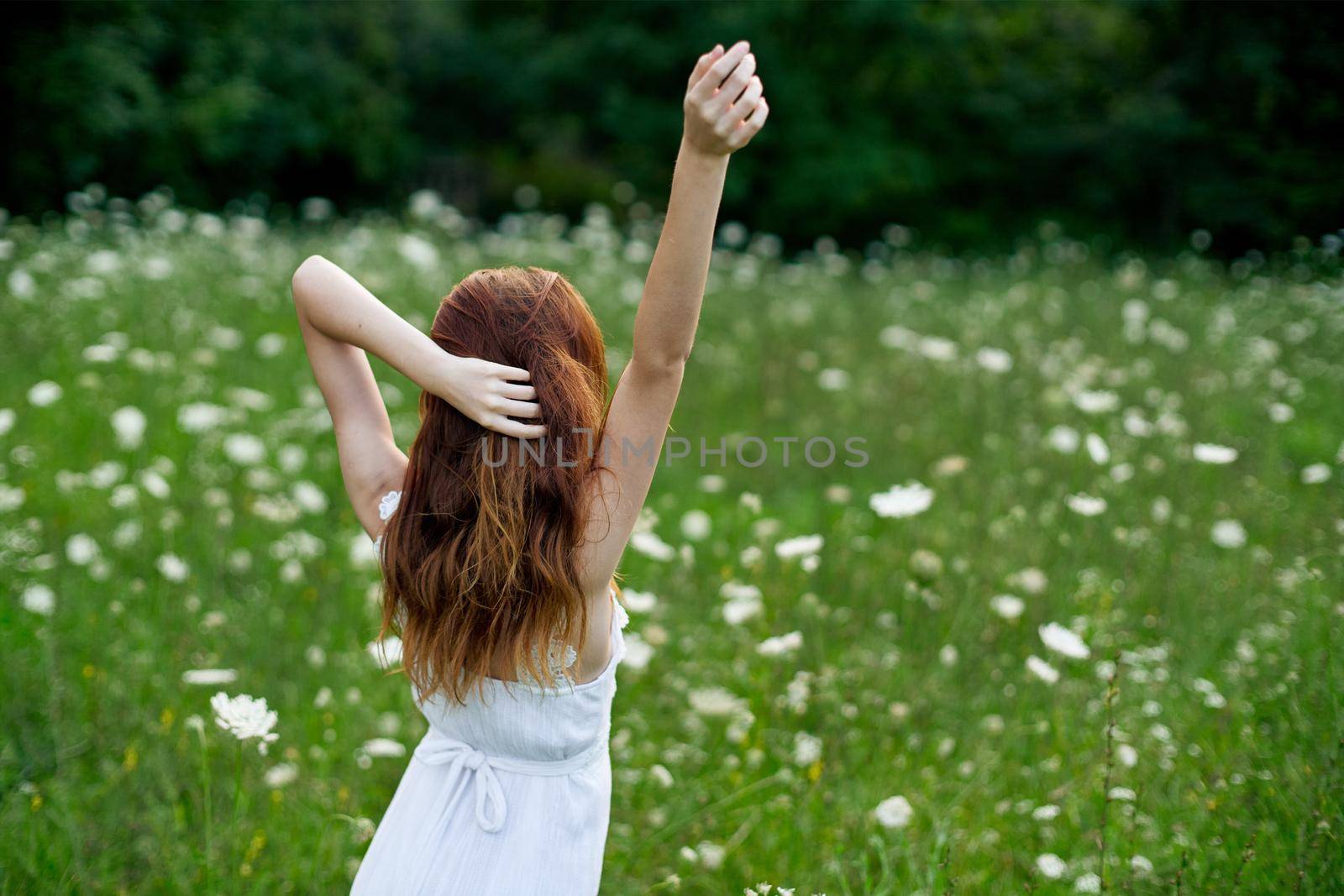 Woman in white dress in a field of flowers walk freedom. High quality photo