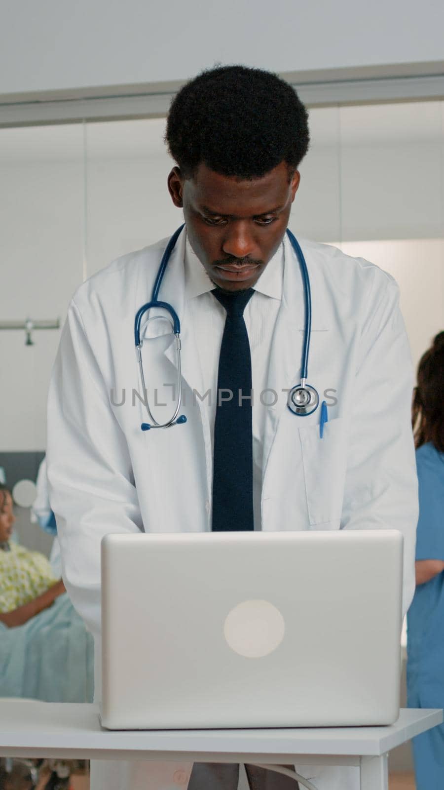 Doctor using laptop to treat patient in hospital ward by DCStudio
