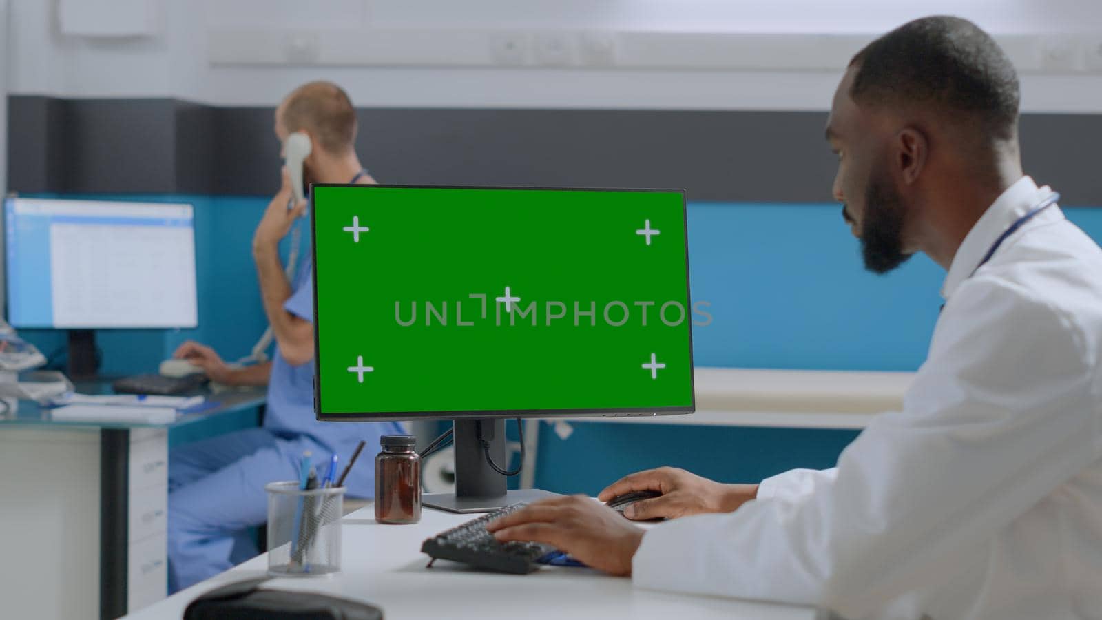 African american specialist doctor analyzing medical report typing sickness expertise on mock up green screen chroma key computer with isolated display. Multi-ethnic team working in hospital office
