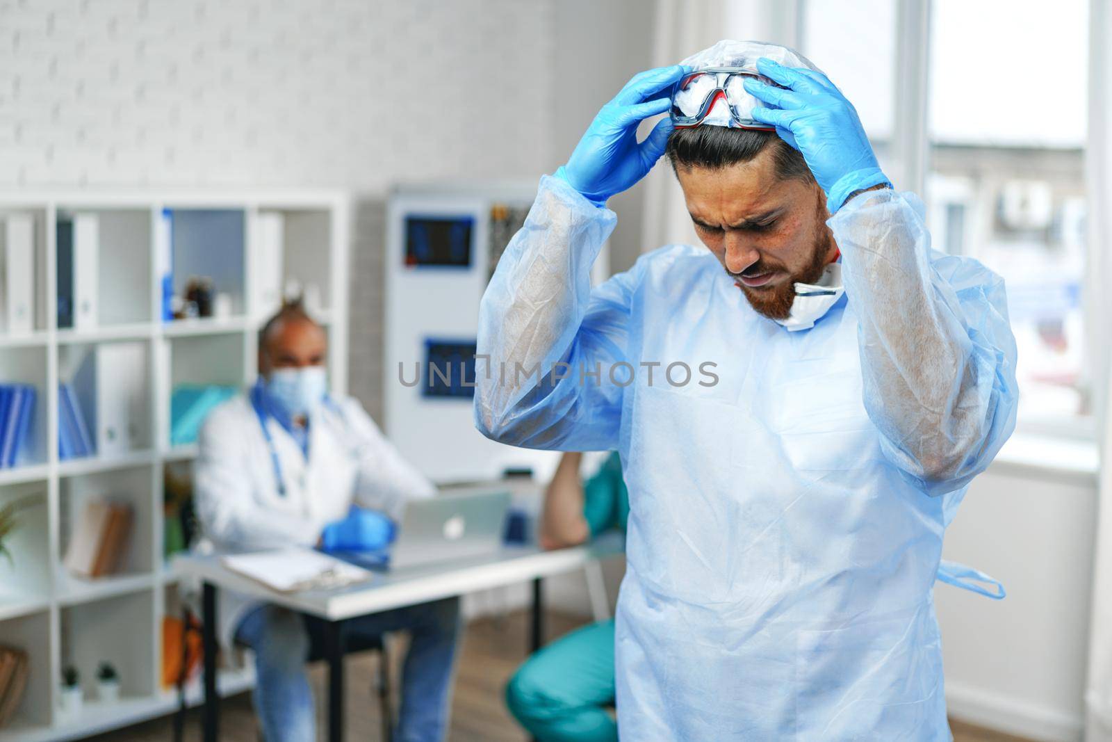 Male doctor in protective medical gown standing in hospital cabinet, portrait