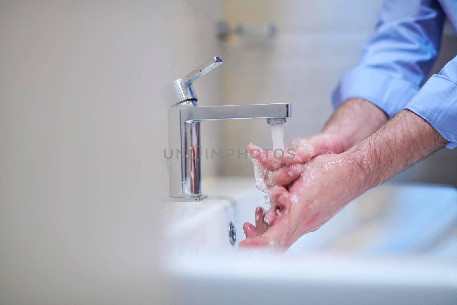 Coronavirus infection and spreading prevention, proper Washing hands with liquid soap. Hygiene male antibacterial hands water wash closeup in bathroom.