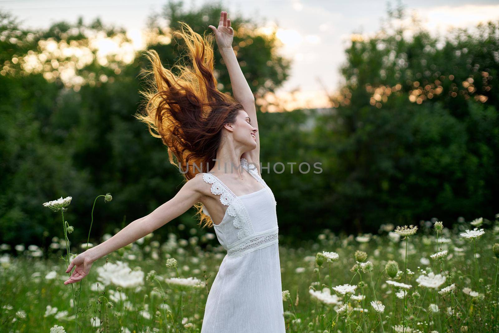 Woman in white dress in a field flowers sun nature freedom. High quality photo