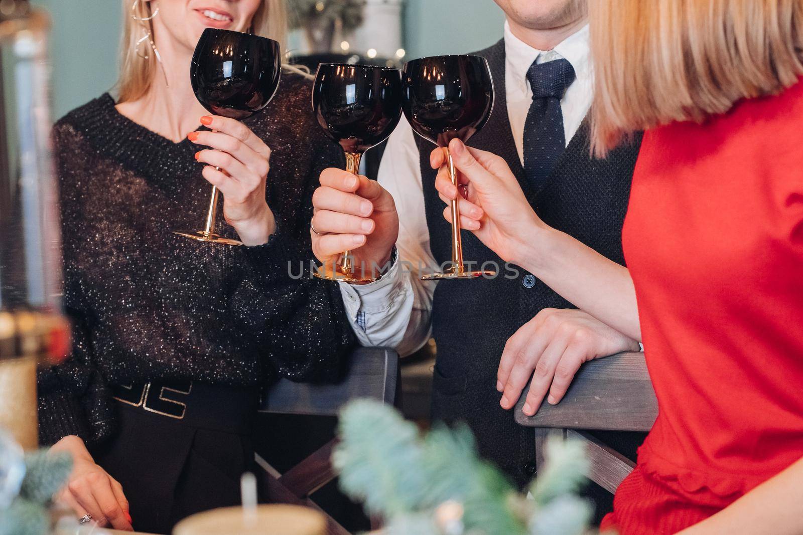 Cropped photo of happy man and women holding glasses during a toast