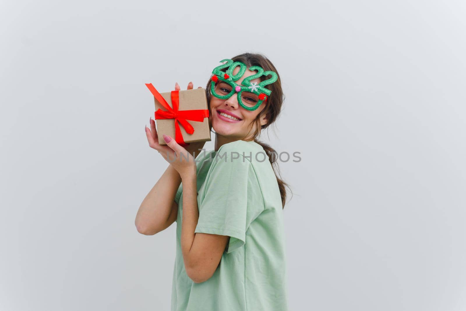 Photo of an amazed happy young woman with a smile hold a hand a Christmas gift isolated on a white background.