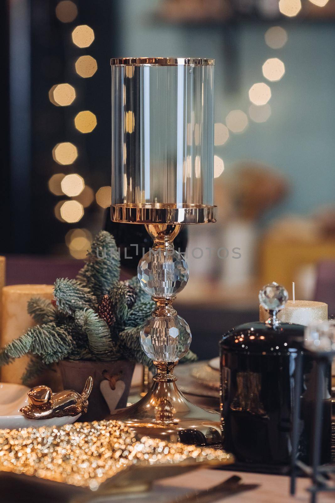 Close up of high glass candlestick on table near Christmas decoration. New Year eve concept