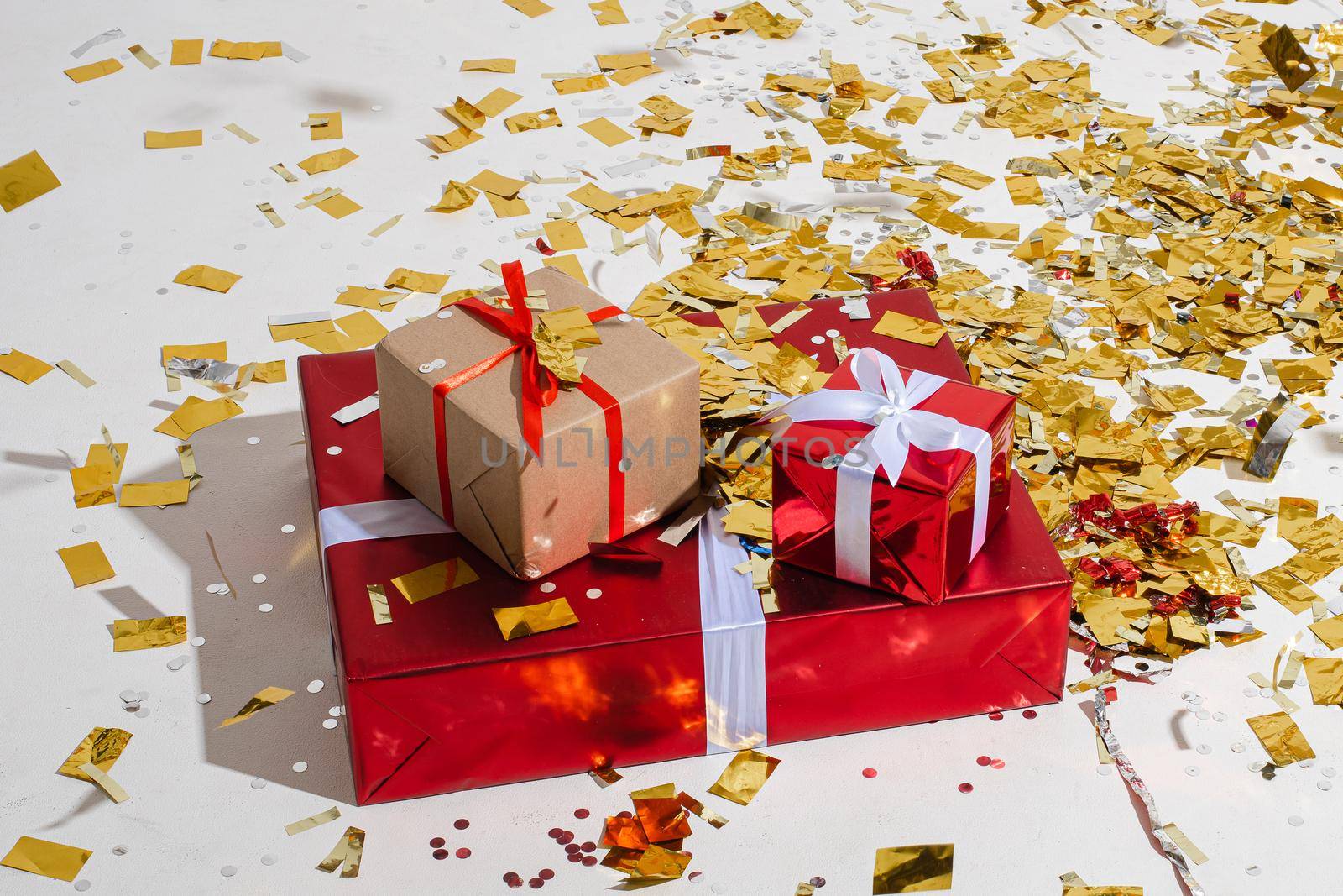 No people image of three gift boxes placed on the floor covered with gold confetti. New year and happy holiday concept
