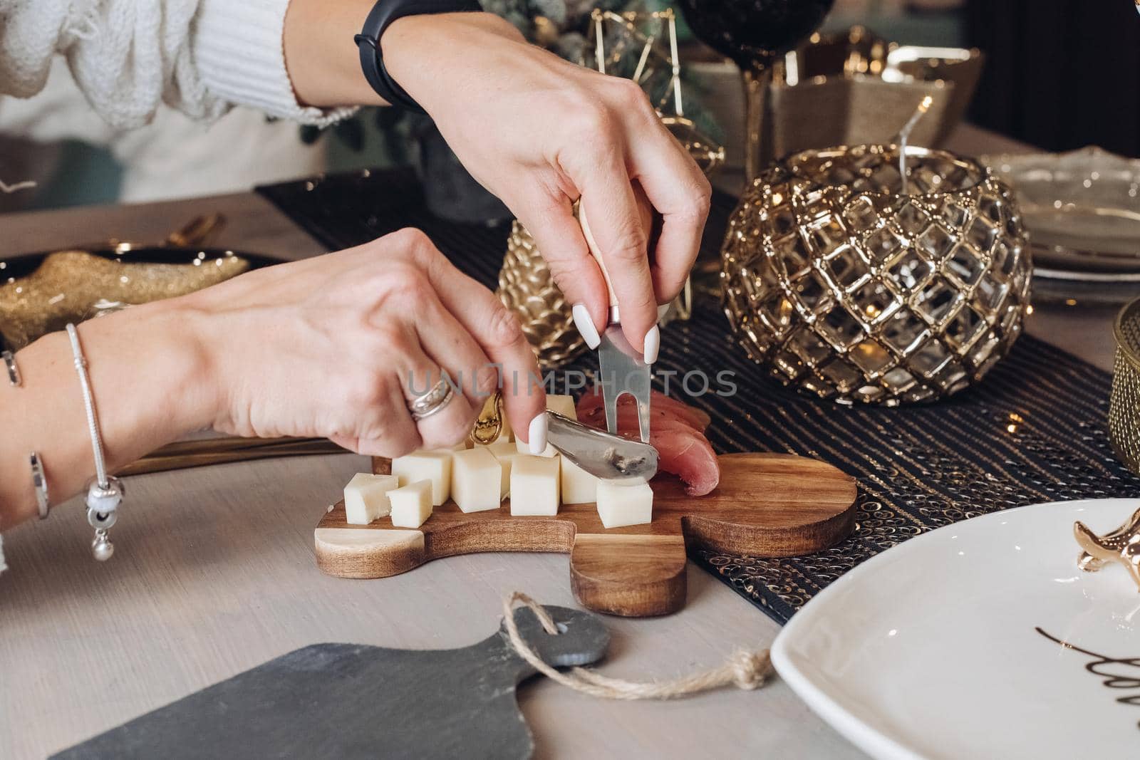Female hands slicing a piece of cheese at the festive table by StudioLucky