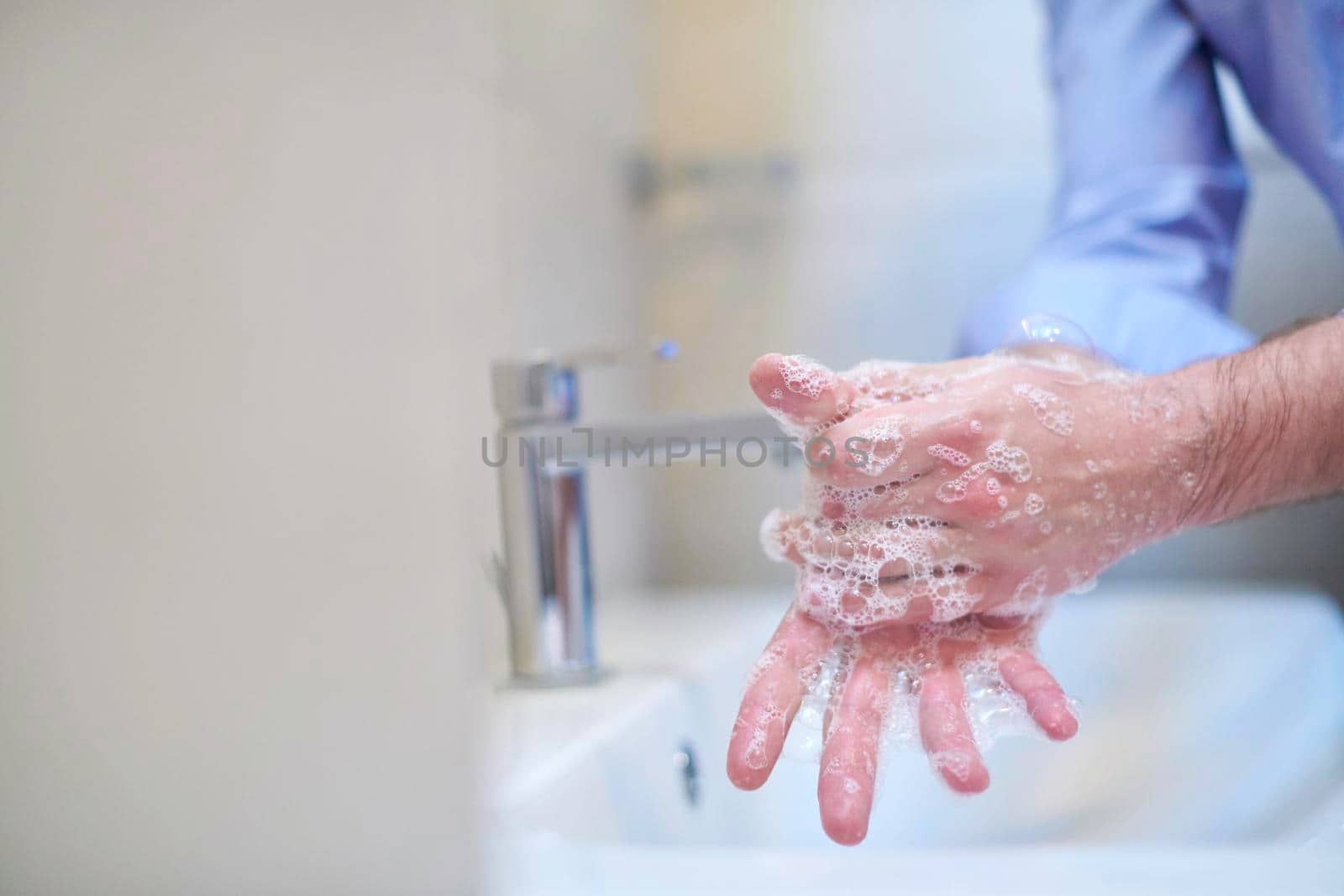 Coronavirus infection and spreading prevention, proper Washing hands with liquid soap. Hygiene male antibacterial hands water wash closeup in bathroom.