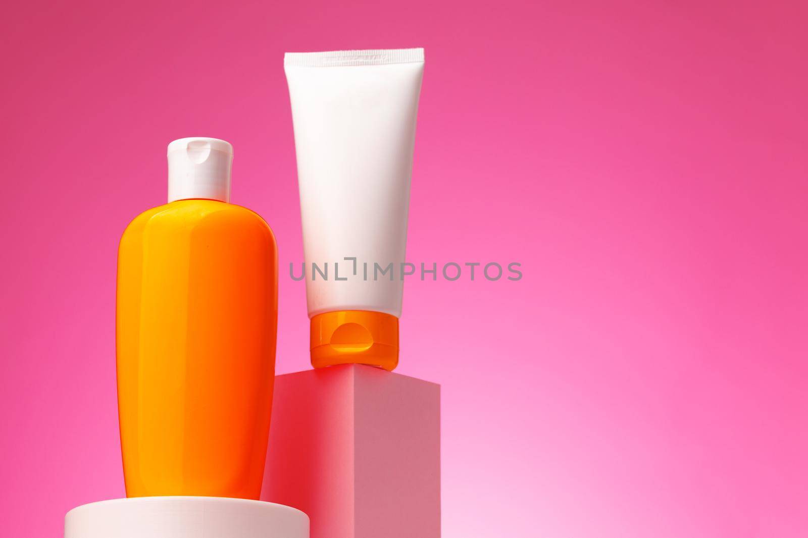 Skincare beauty products container against pink background, copy space