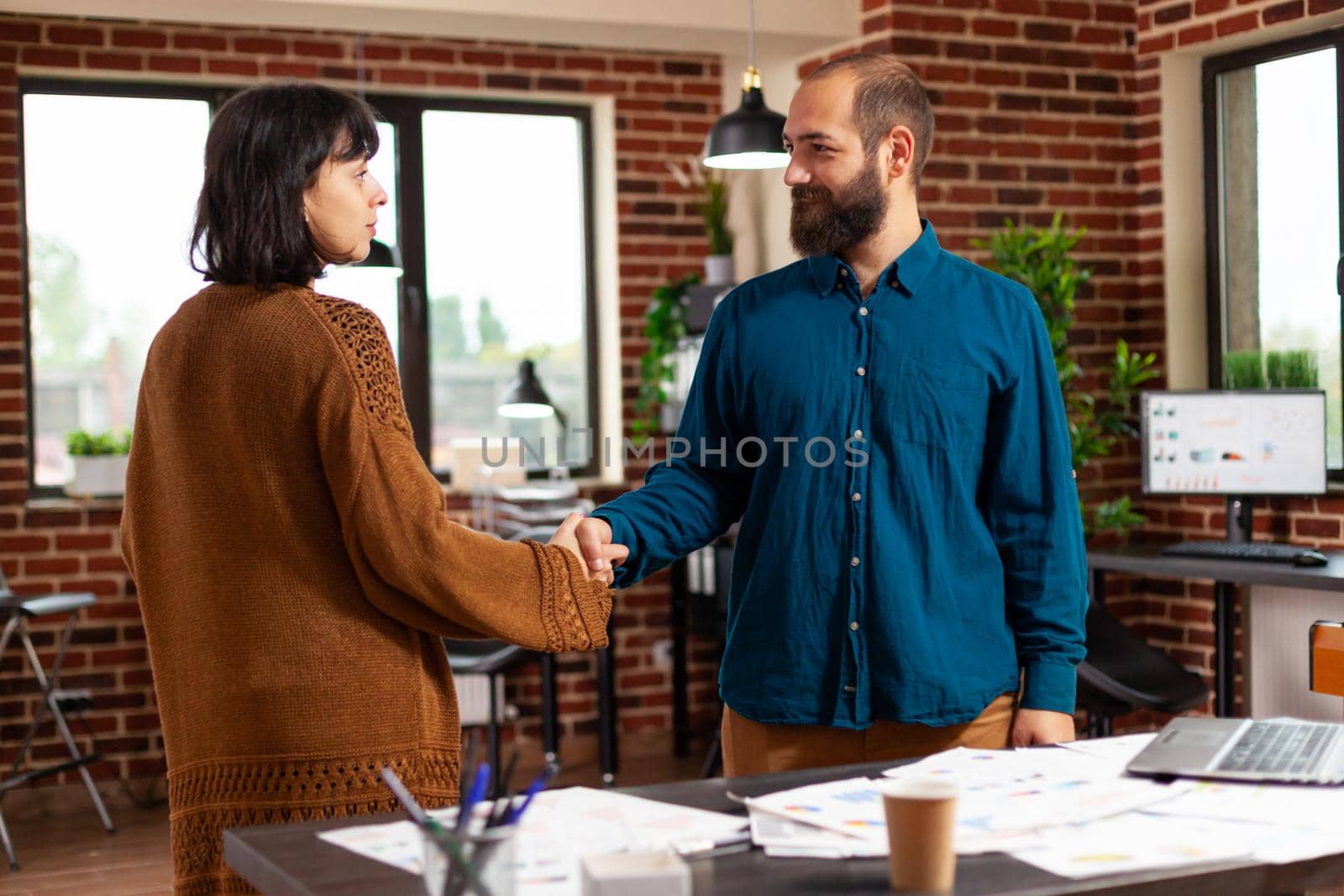 Businesspeople shaking hands during business meeting in startup office working at company investment preparing marketing presentation. Financial team analyzing management papaerwork with strategy