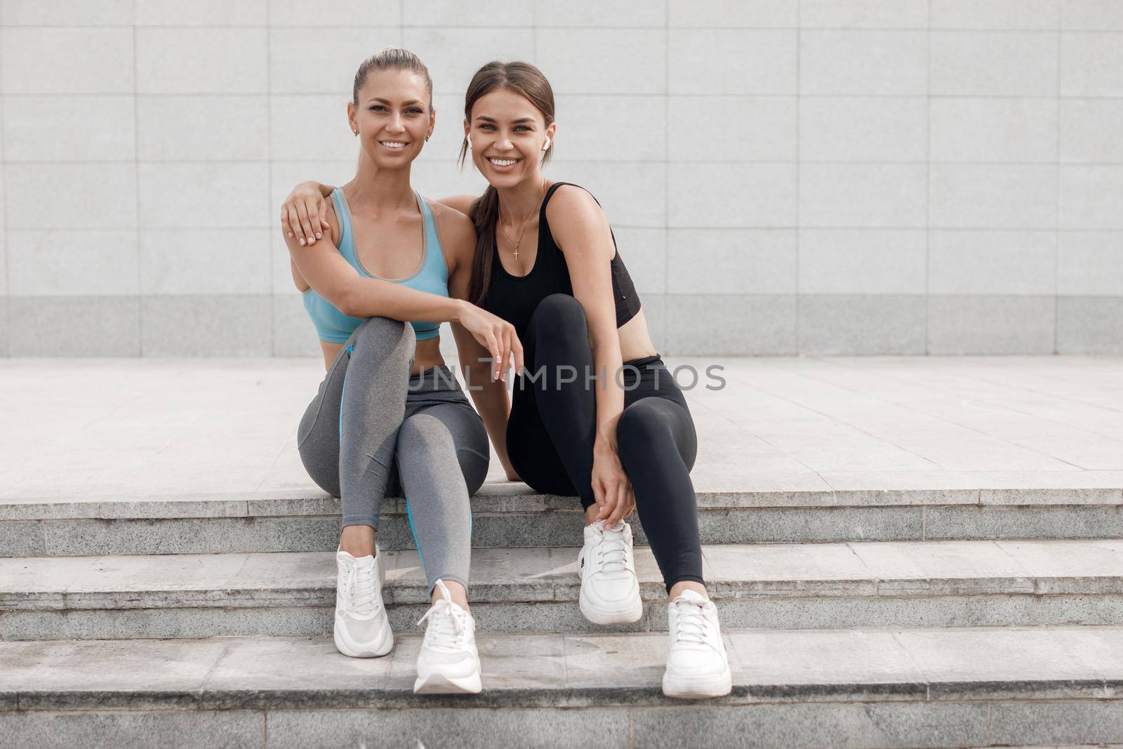 Two women relaxing after training outdoor by splash