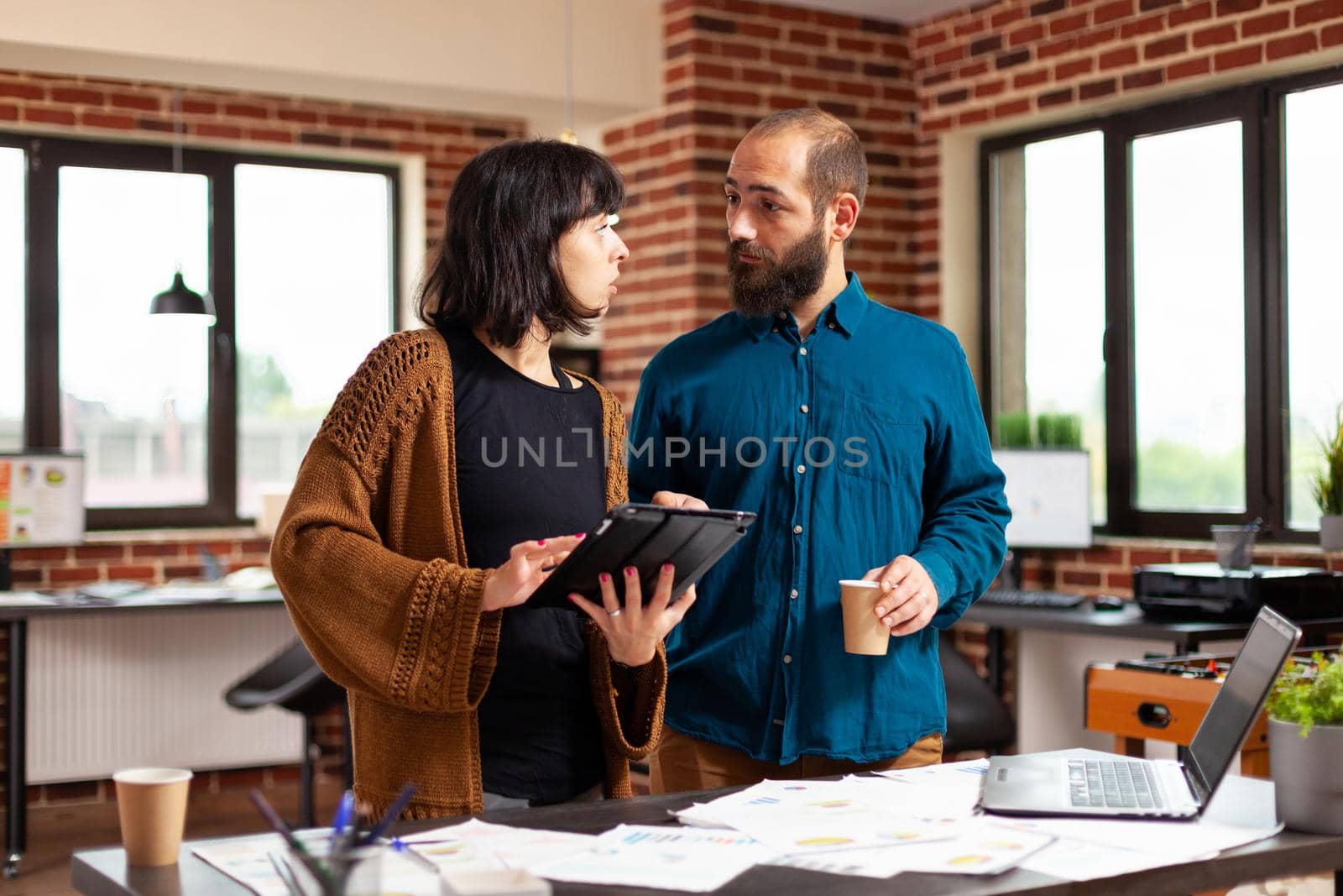 Businesswoman holding tablet computer showing business report to man collegue by DCStudio