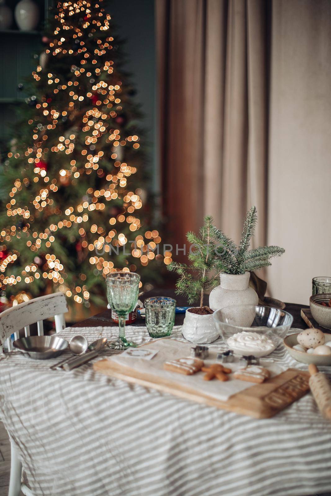 View over modern kitchen with white cupboards and brown table decorated with natural green fir tree branches and Christmas wreath. Christmas decorations.