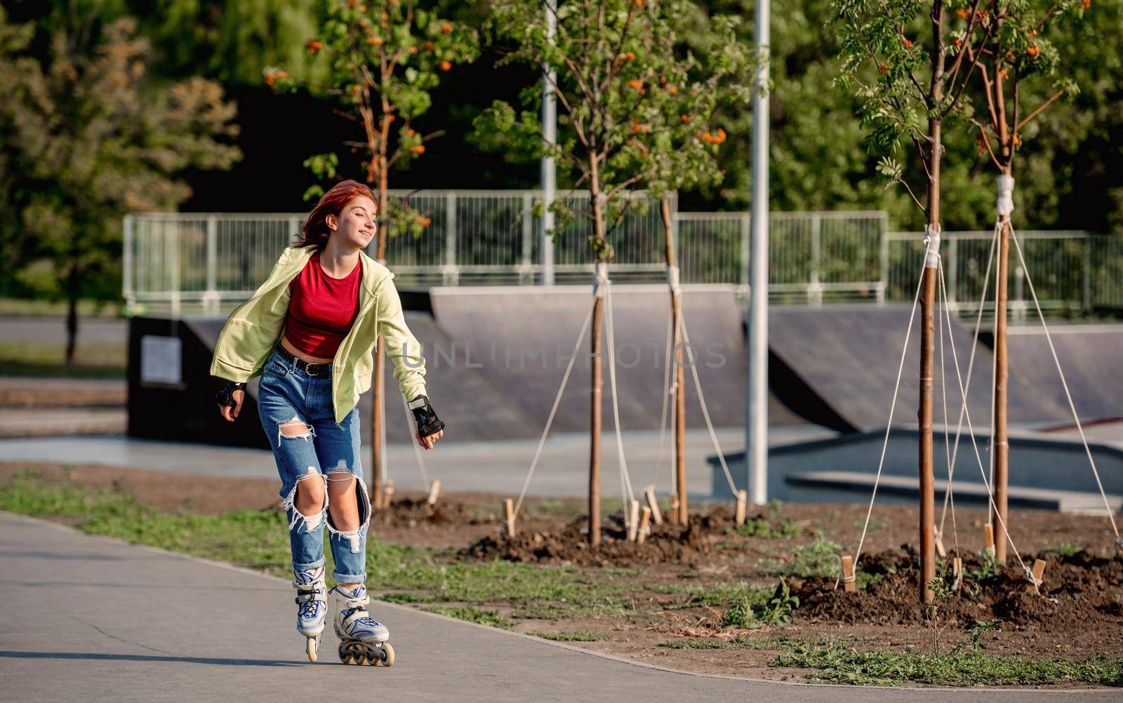 Pretty girl on roller skates enjoying riding in city at summer. Beautiful female teenager rollerblading and happy smiling