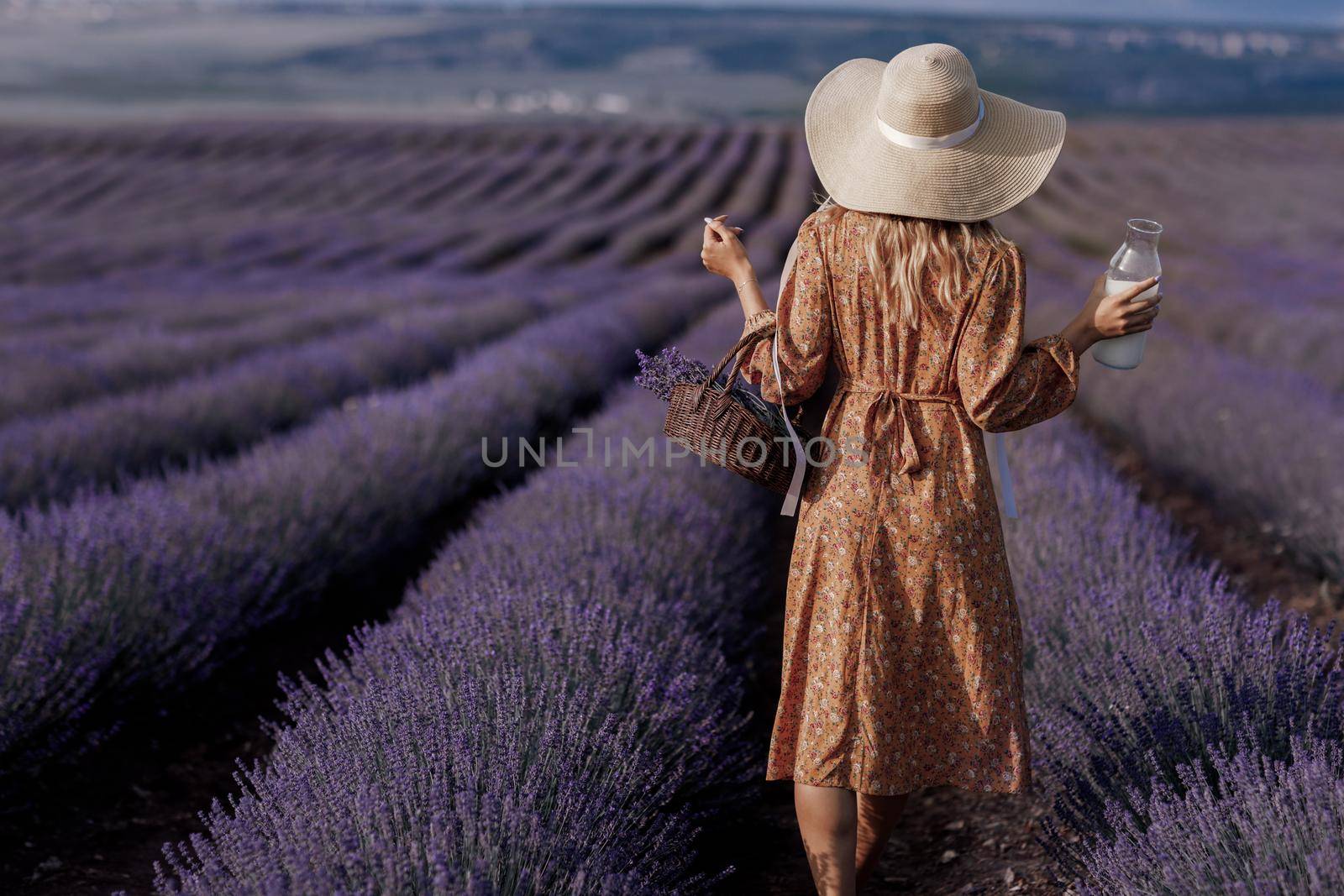 Fashion portrait of a pretty young woman in lavender field back view by splash
