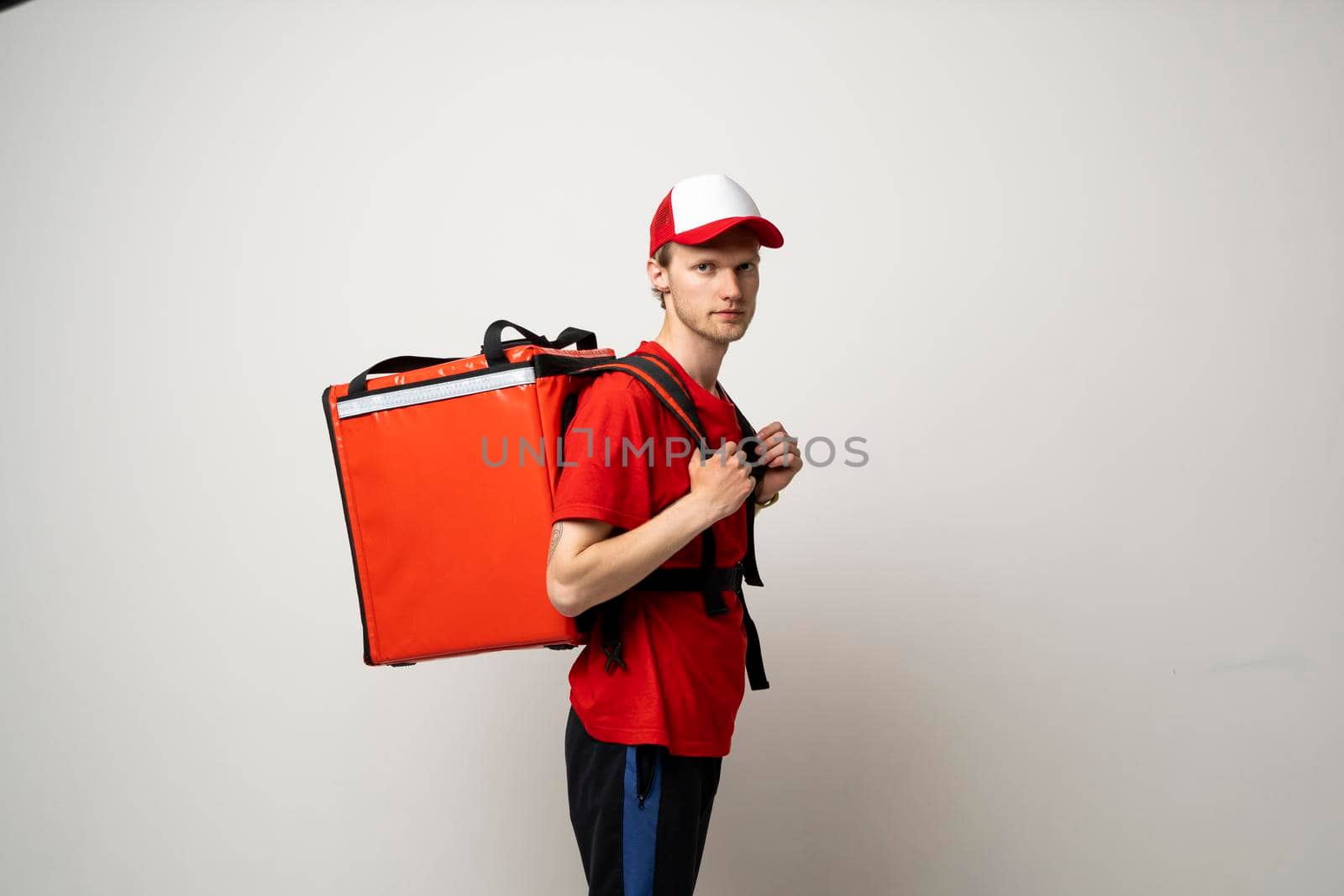 Portraite of delivery man in red t-shirt uniform thermal bag backpack with food isolated on white background studio. Fast Food Delivery Service Cocnept. by vovsht