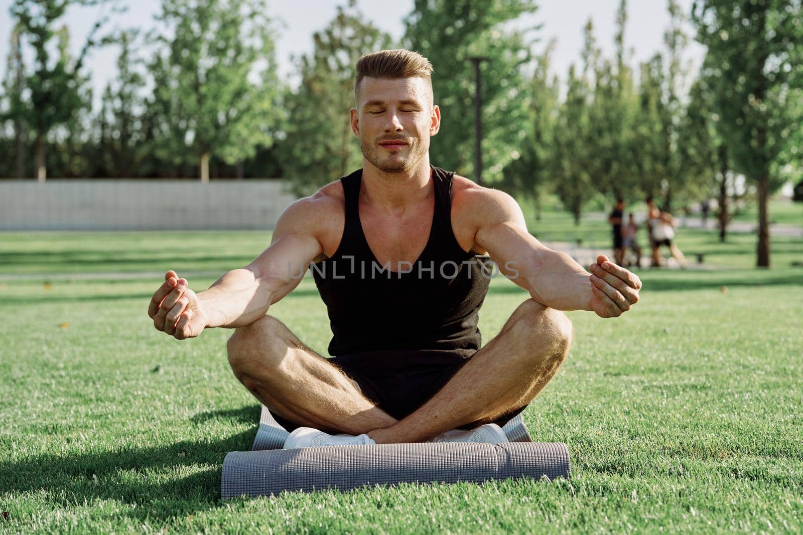 sporty man sitting on the lawn in the park training. High quality photo