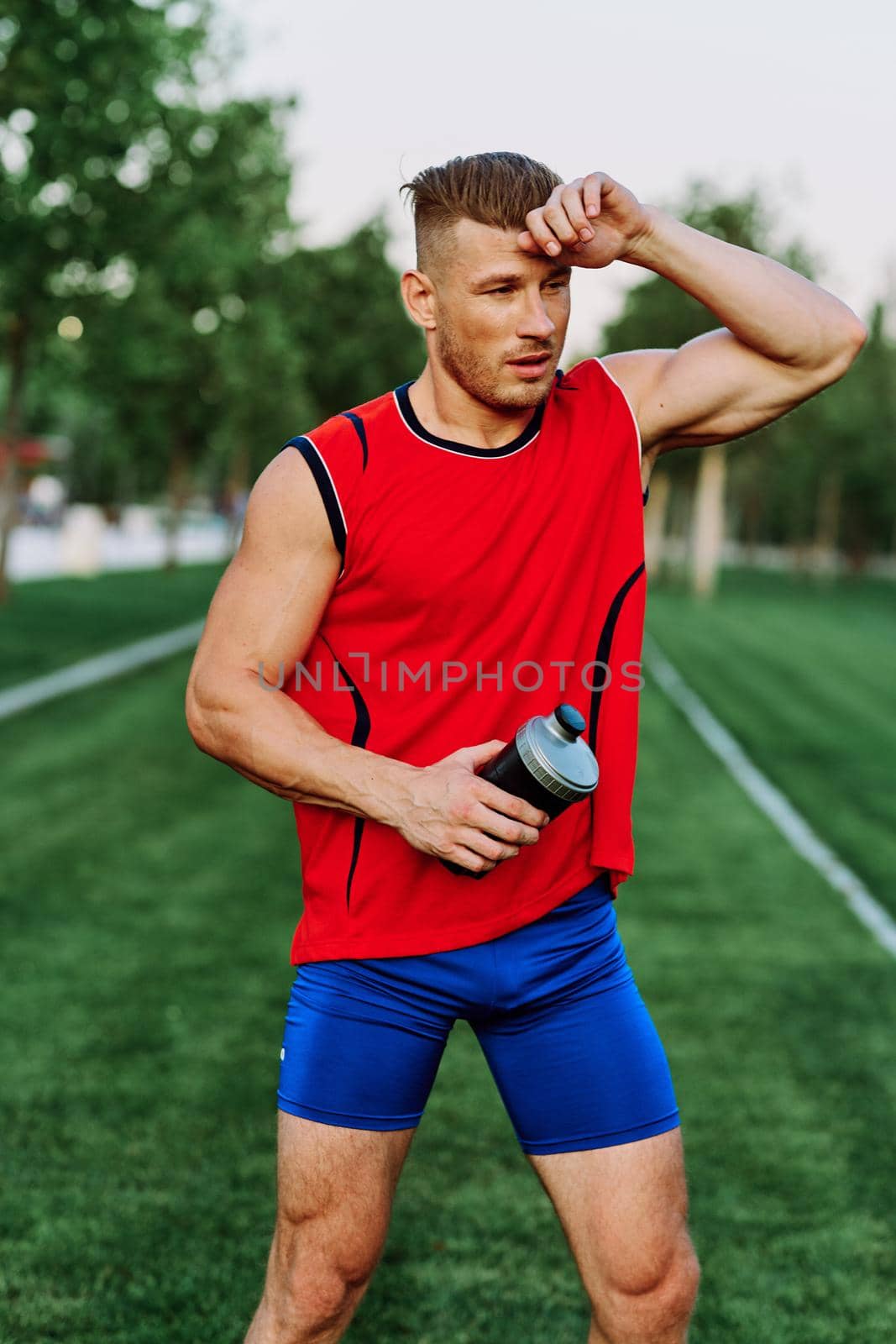 Cheerful sporty man in the park on green grass doing exercises by Vichizh